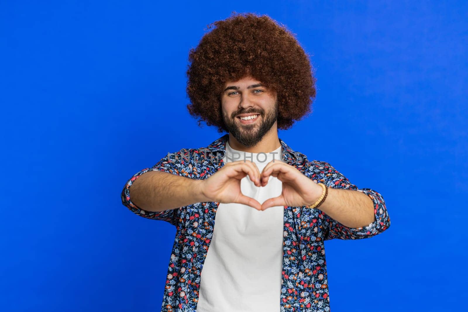 Smiling lovely man makes heart gesture demonstrates love sign expresses good feelings and sympathy by efuror