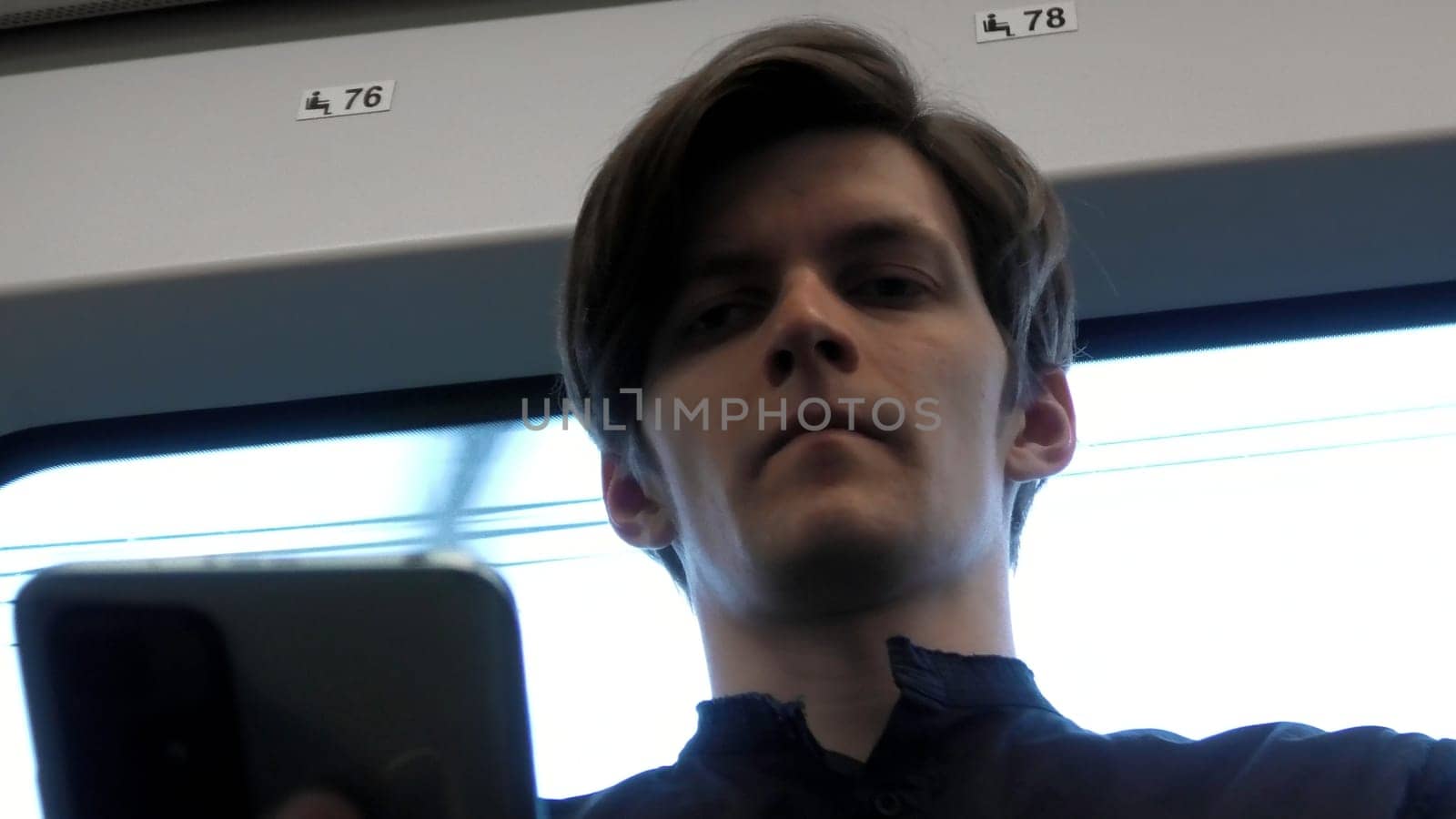 Caucasian man looking down on phone and looking stressed. Stock clip. Face of a man sitting near the window in the tram or bus. by Mediawhalestock