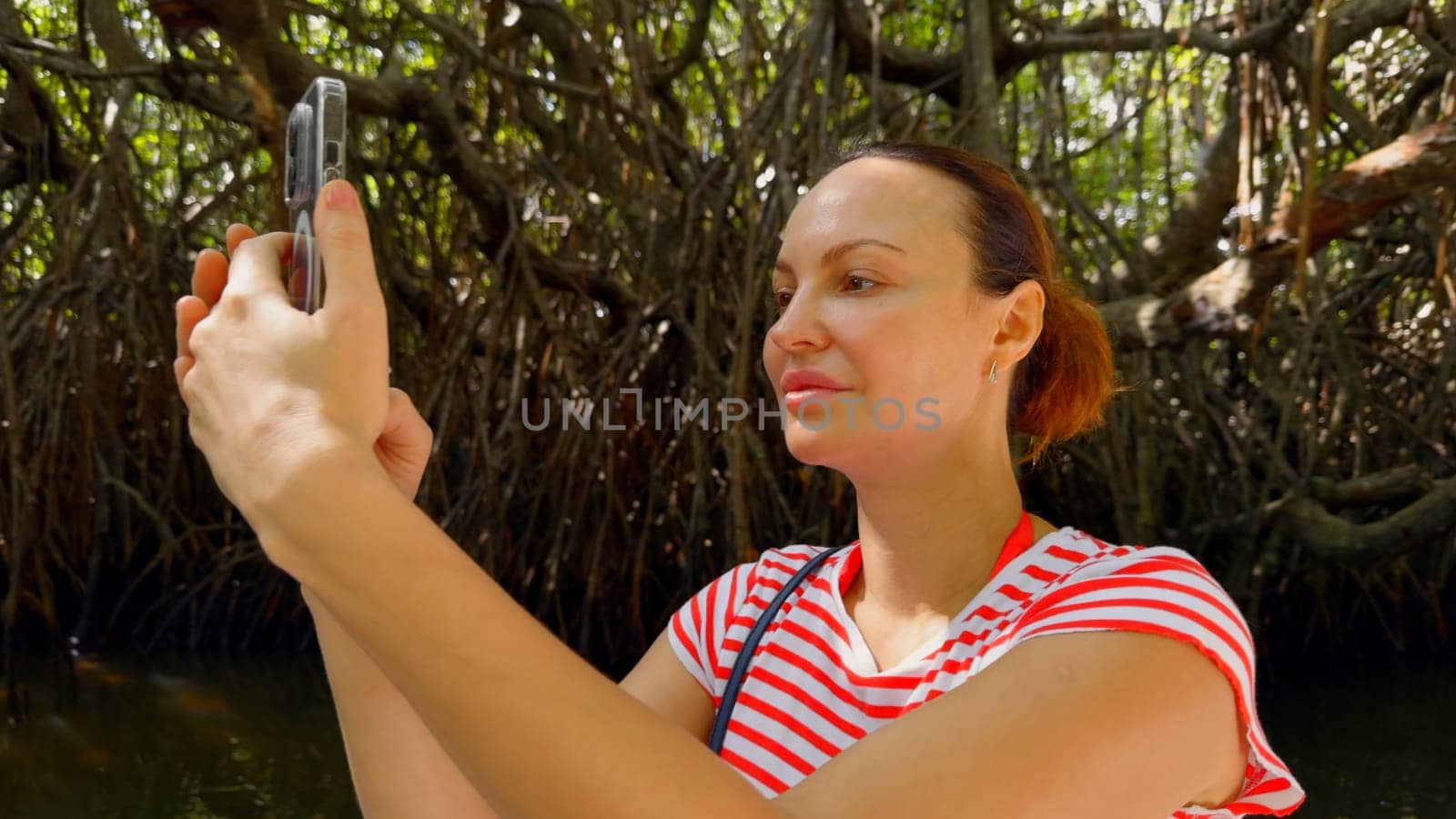 Jungle cruise down a swampy river, Costa Rica. Action. Portrait of female tourist making pictures and videos of surrounding nature