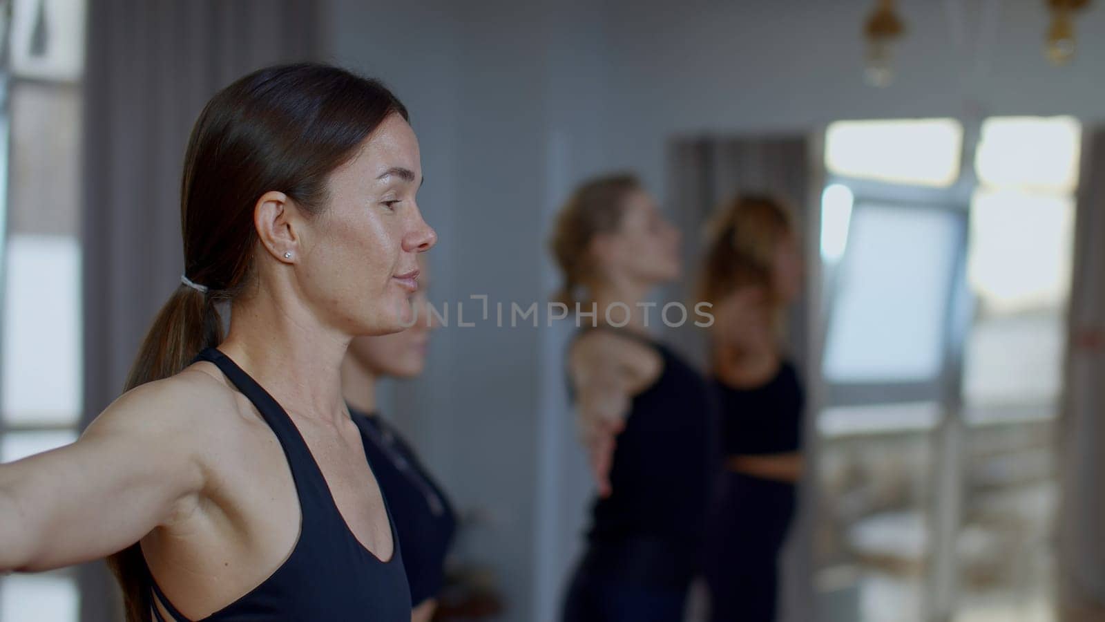 Woman coach performing training workout for female group. Media. Mentor explaining the technique of breathing with hands swings