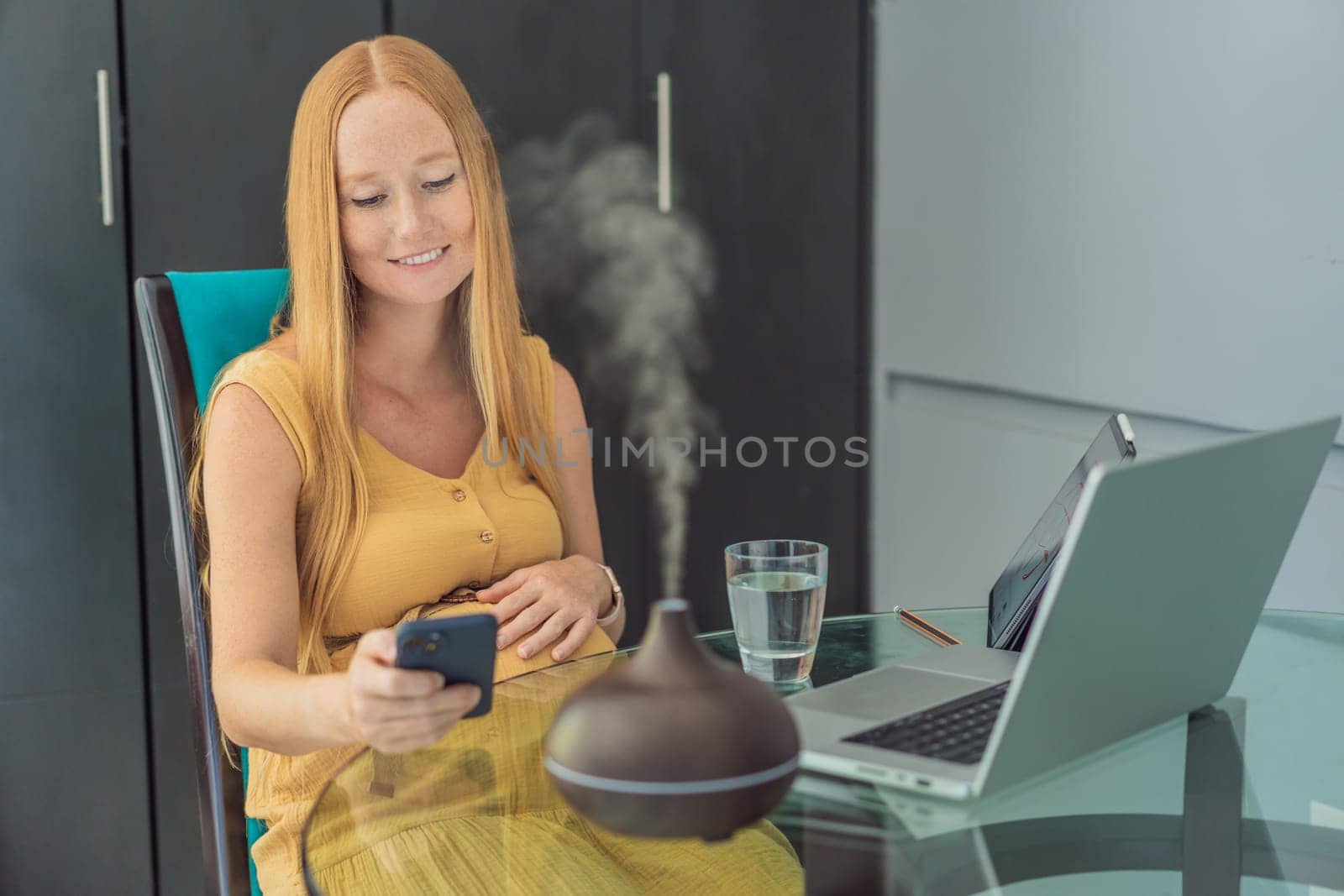 Expectant woman enhances work environment, using an aroma diffuser for a soothing atmosphere during pregnancy by galitskaya