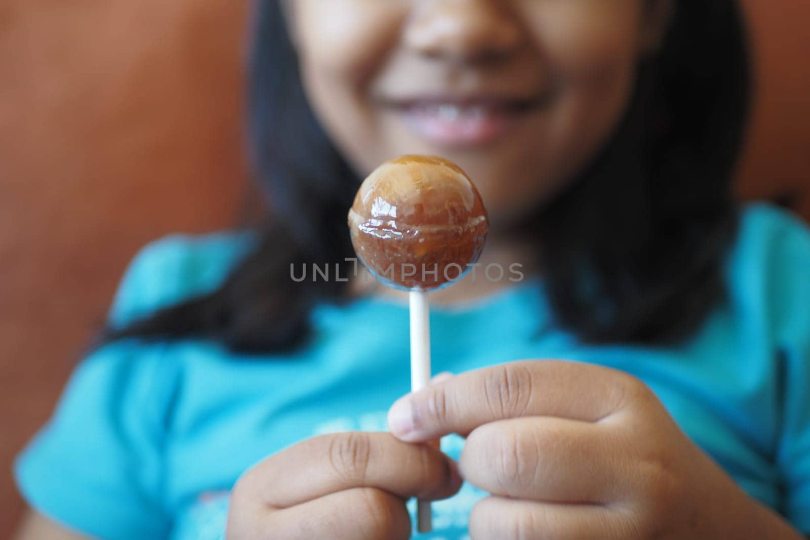 child is licking colorful candy on stick,