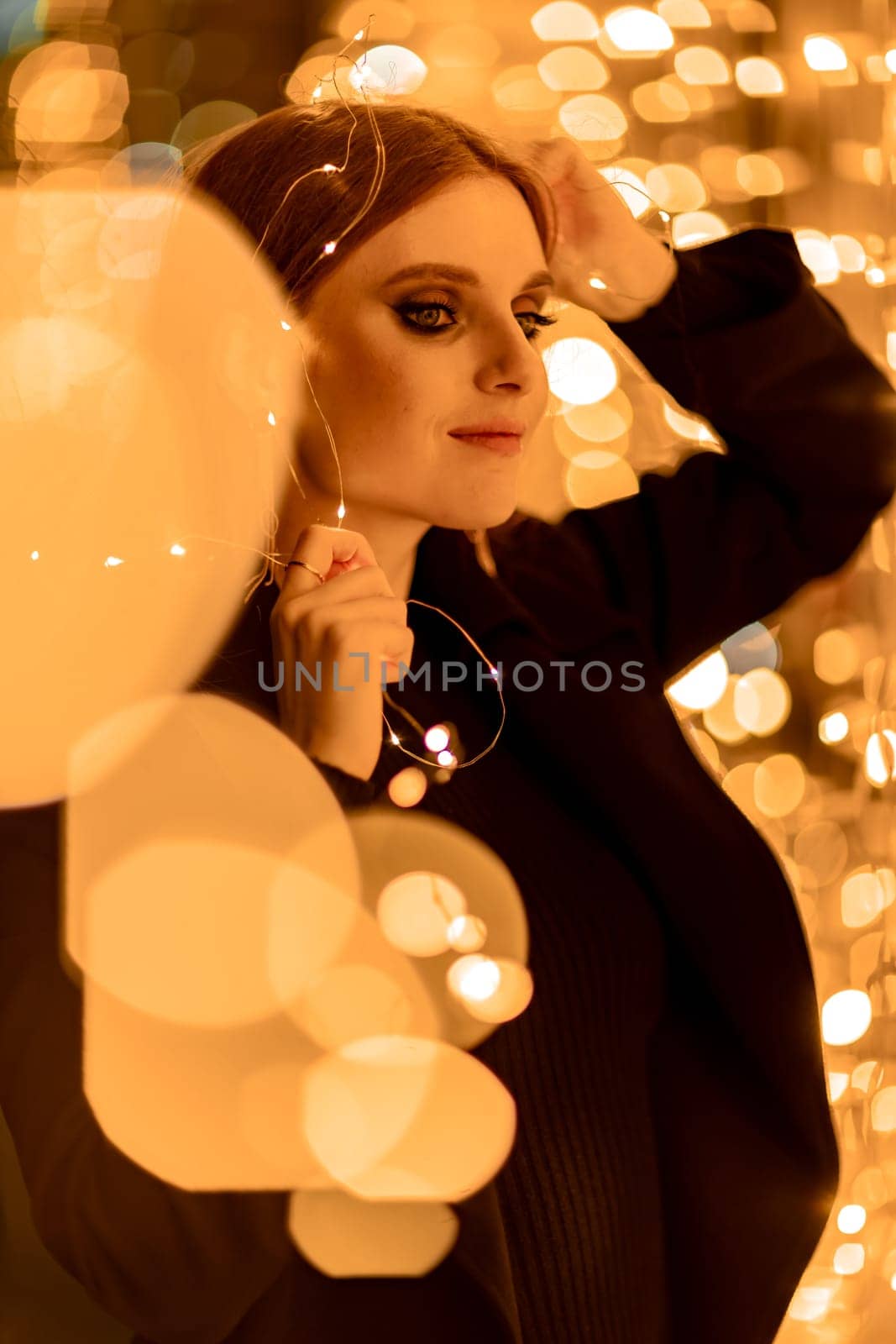 Christmas mood. Woman with long hair in sity decorated for Christmas. She is dressed in a black coat