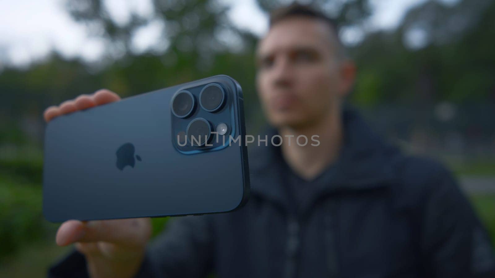 UK, London - September 15, 2023: Man takes pictures on new iPhone. Action. Apple's logo on new iPhone 15 pro. Shooting on new iPhone 15 pro in nature.