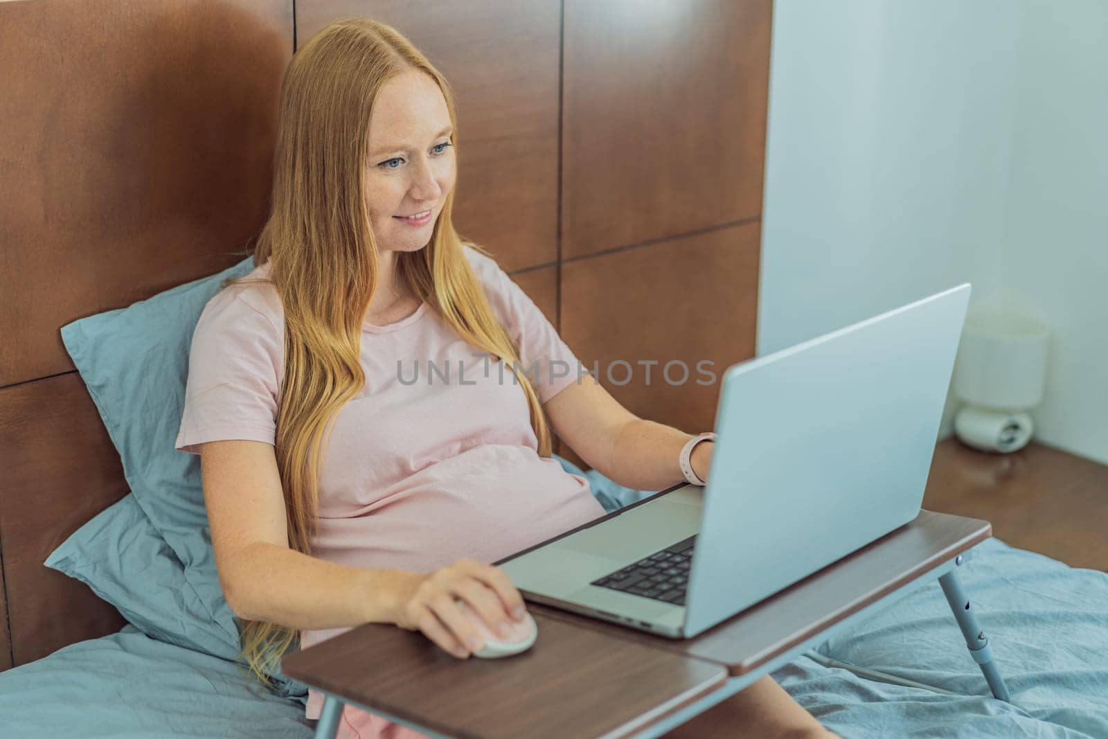 Pregnant woman working on laptop. Expectant woman efficiently works from home during pregnancy, blending professional commitment with maternal duties by galitskaya