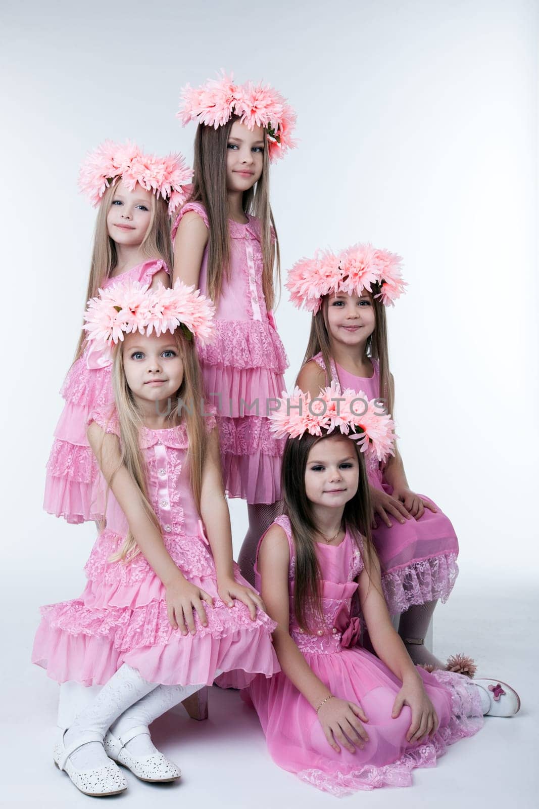 Studio portrait of five little girls in pink dresses and wreaths