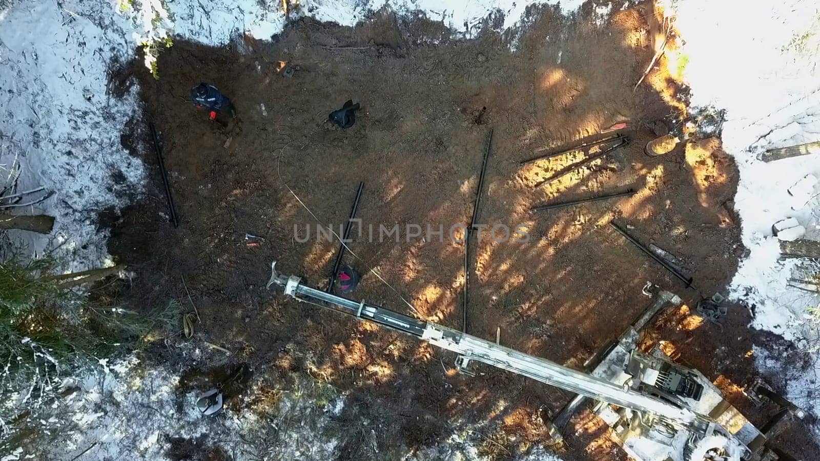 Aerial top view of work on a construction site during winter. Clip. Workers and equipment for works with cold ground