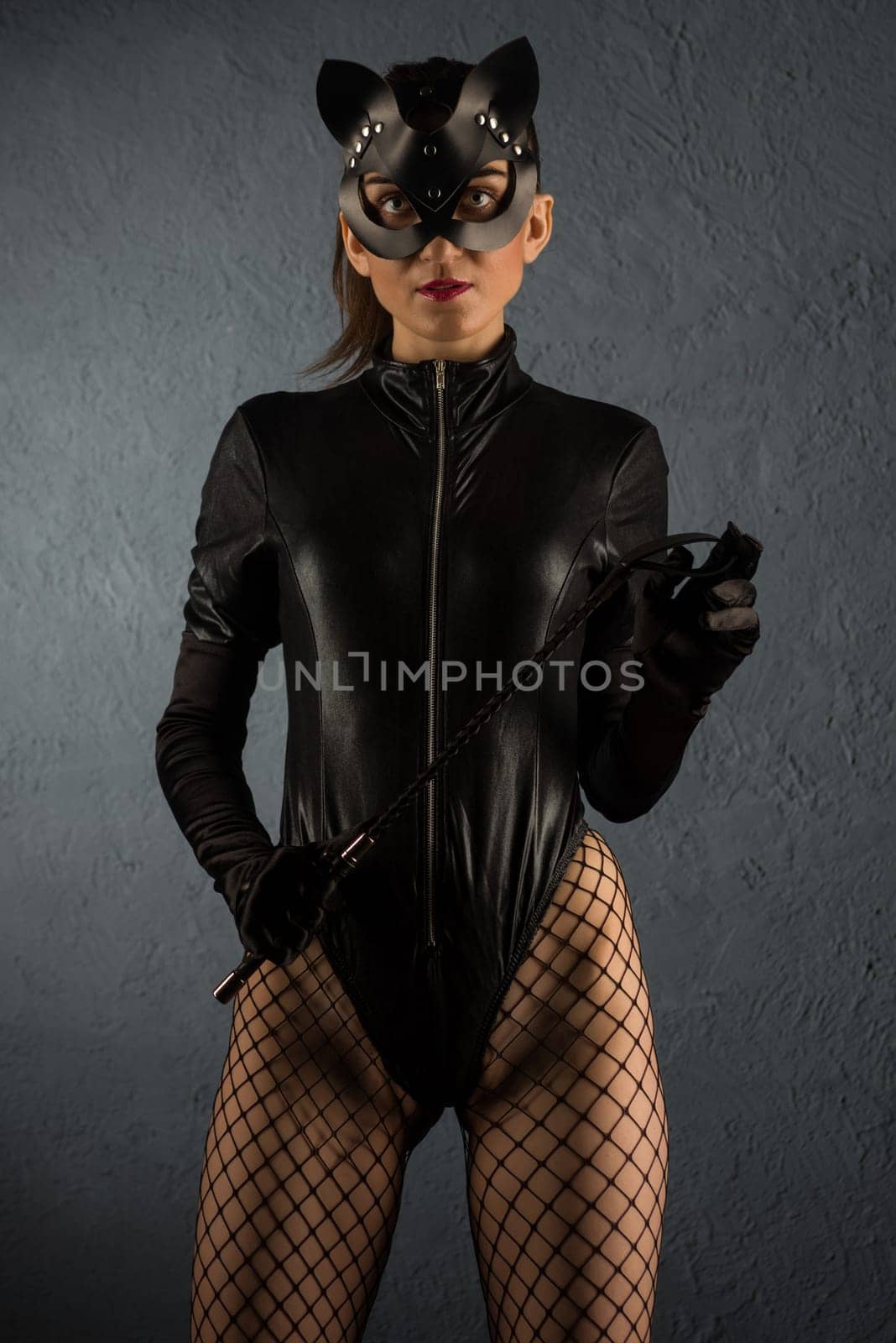 Beautiful dominant brunette mistress girl in latex body, gloves and bdsm black leather fetish cat mask posing with riding crop by zartarn