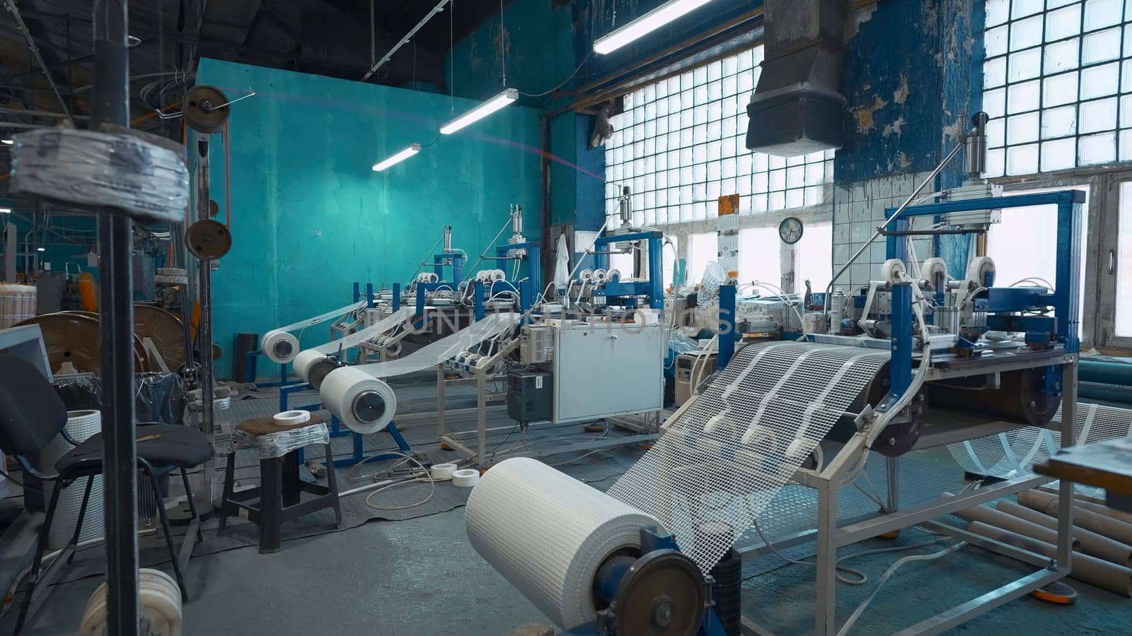 Industrial production of plastic grids. Creative. Machines winding thermoplastic meshes made of polymers. Assembly shop of chemical plant of polymer products.