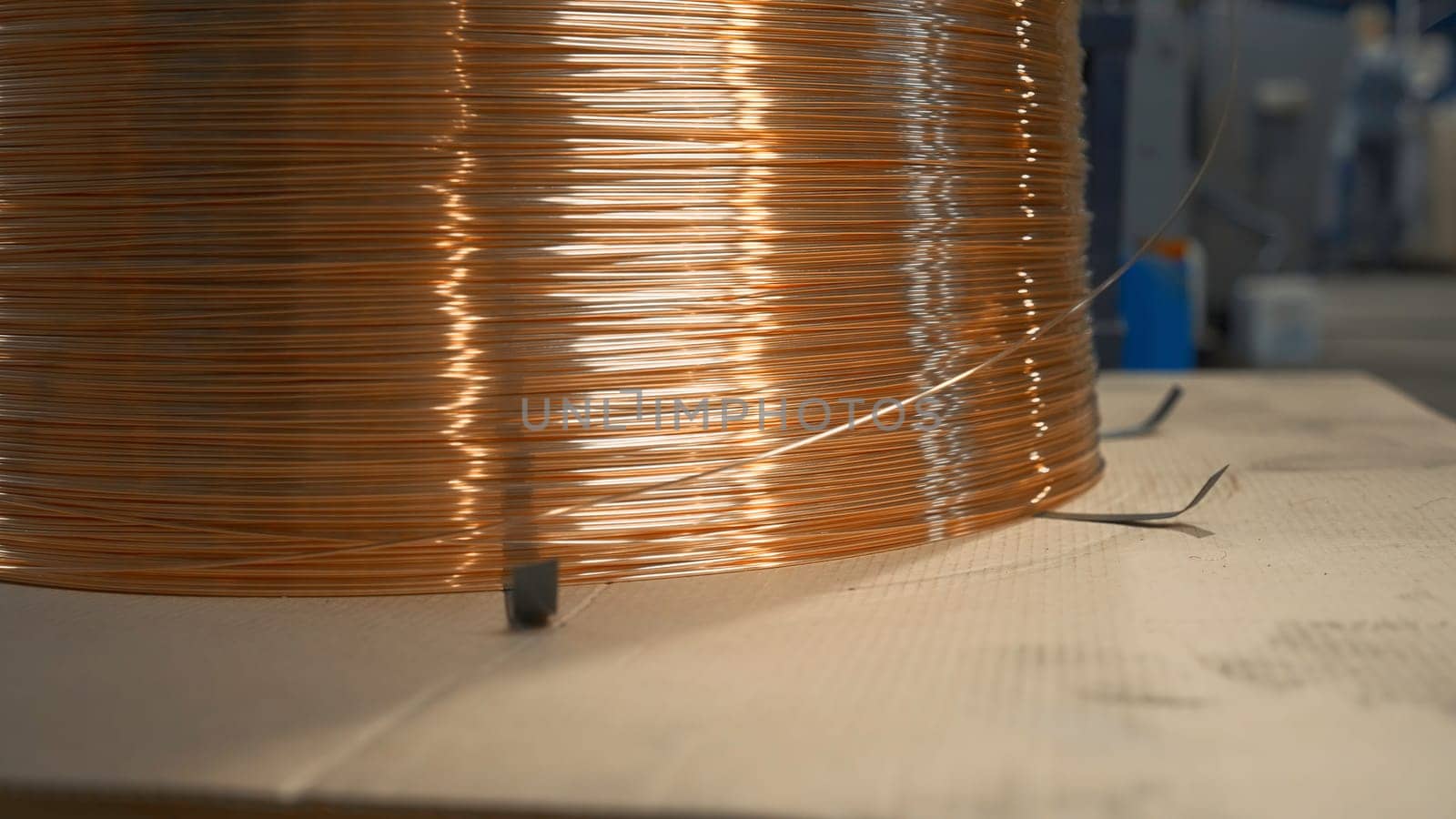 Close-up of wound copper wire in production. Creative. Thin line of wire on industrial coil. Production of copper wire at metallurgical plant.