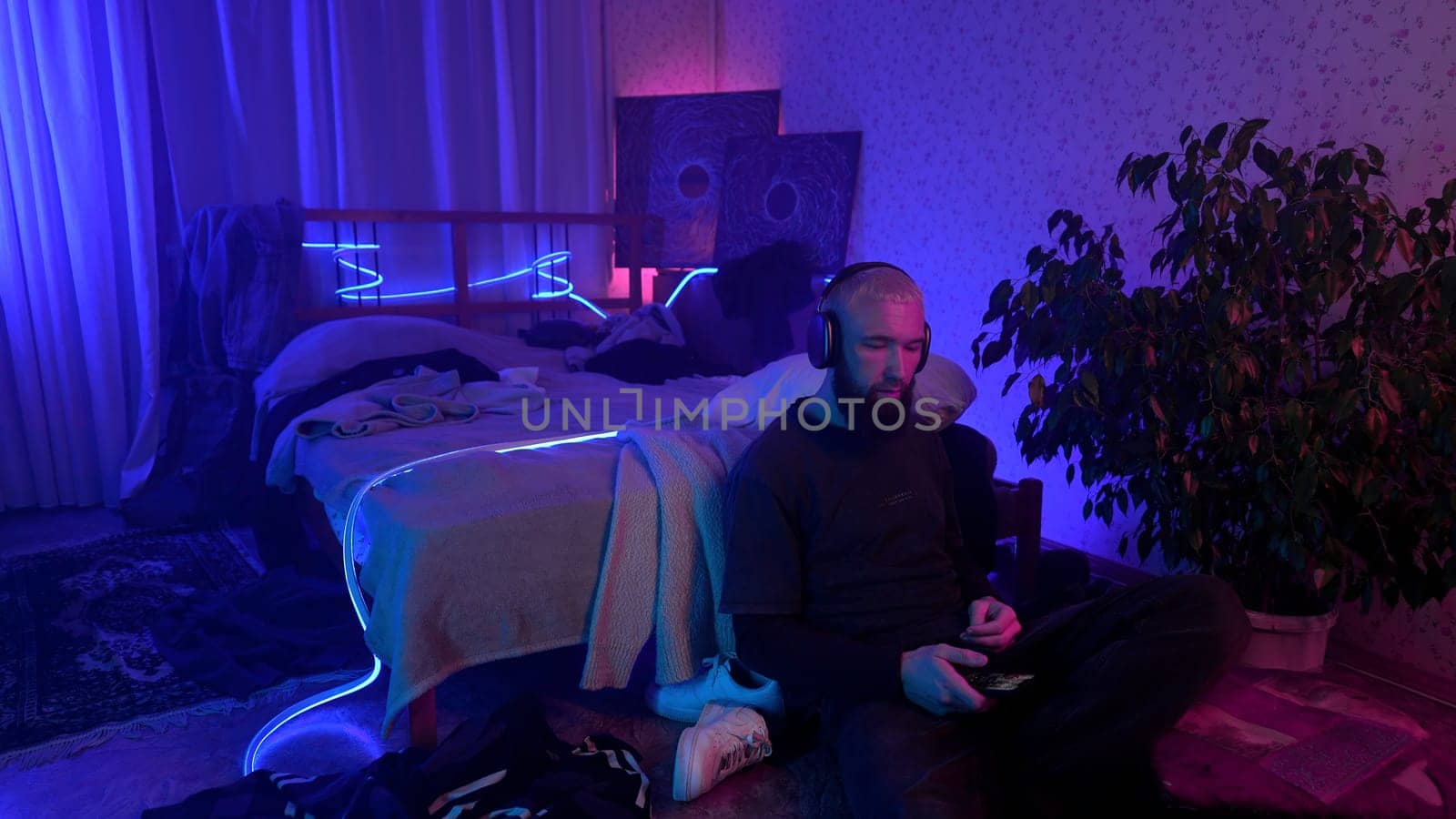 Man using smartphone and listening to music at home. Media. Cozy and messy room of a hipster guy