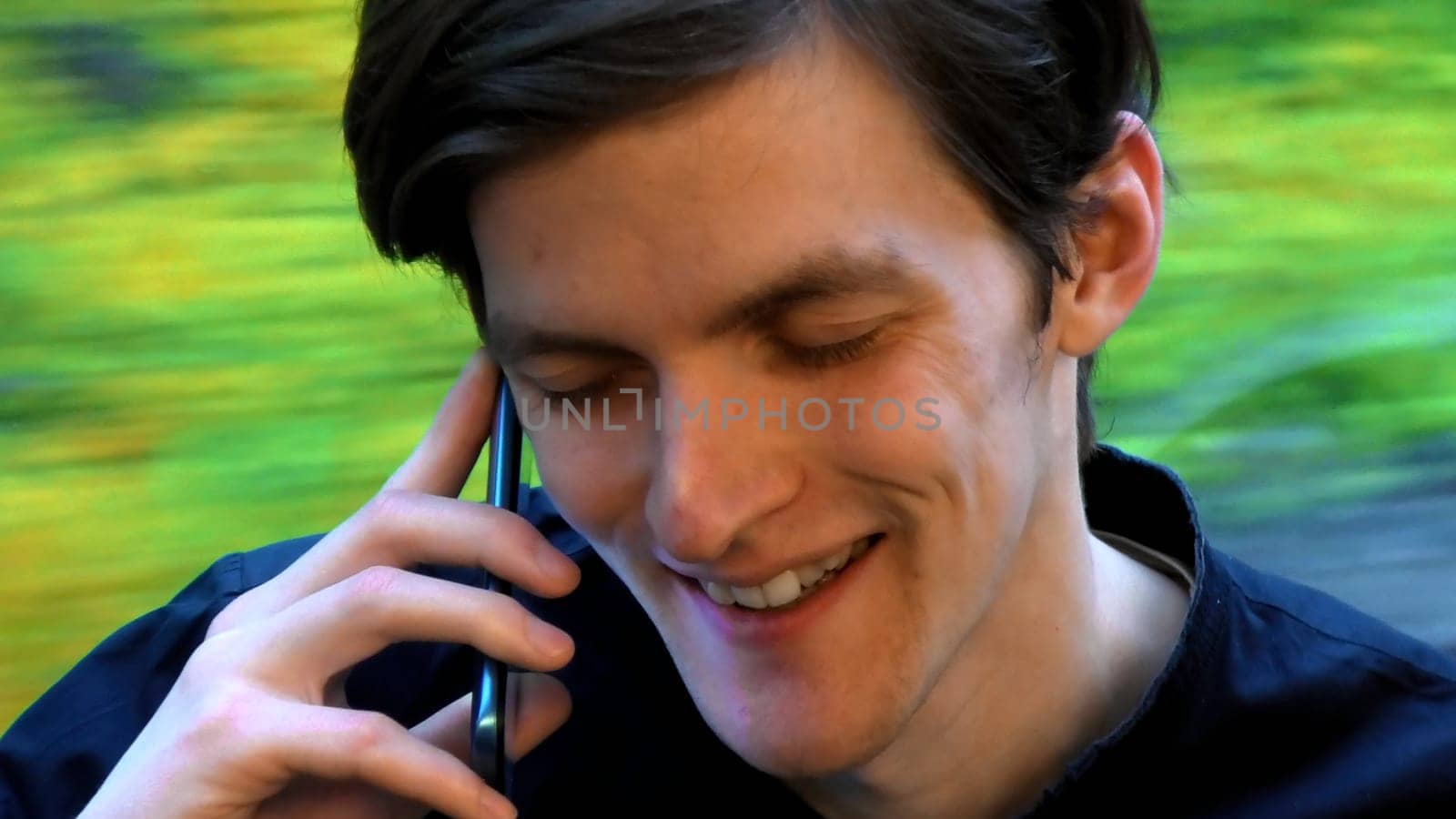 Caucasian man smiling with eyes closed while talking with somebody on the smartphone. Stock clip. Face of a man sitting near the window in the tram or bus