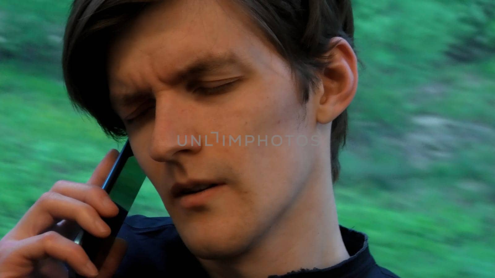 Young caucasian man travel in train and have annoying talk on mobile phone by the train window. Stock clip. Conversation on mobile phone or smartphone