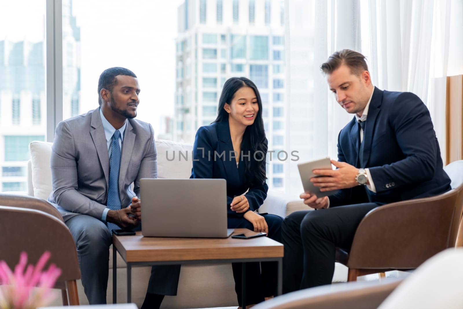 Smart caucasian businessman present marketing idea by using tablet. Group of business team listening while deciding to invest in start up project at modern lounge. Ornamented.