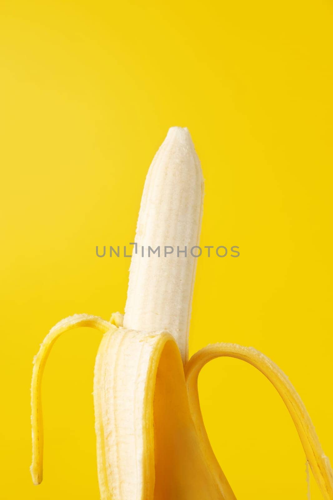 Peeled banana isolated on yellow background.