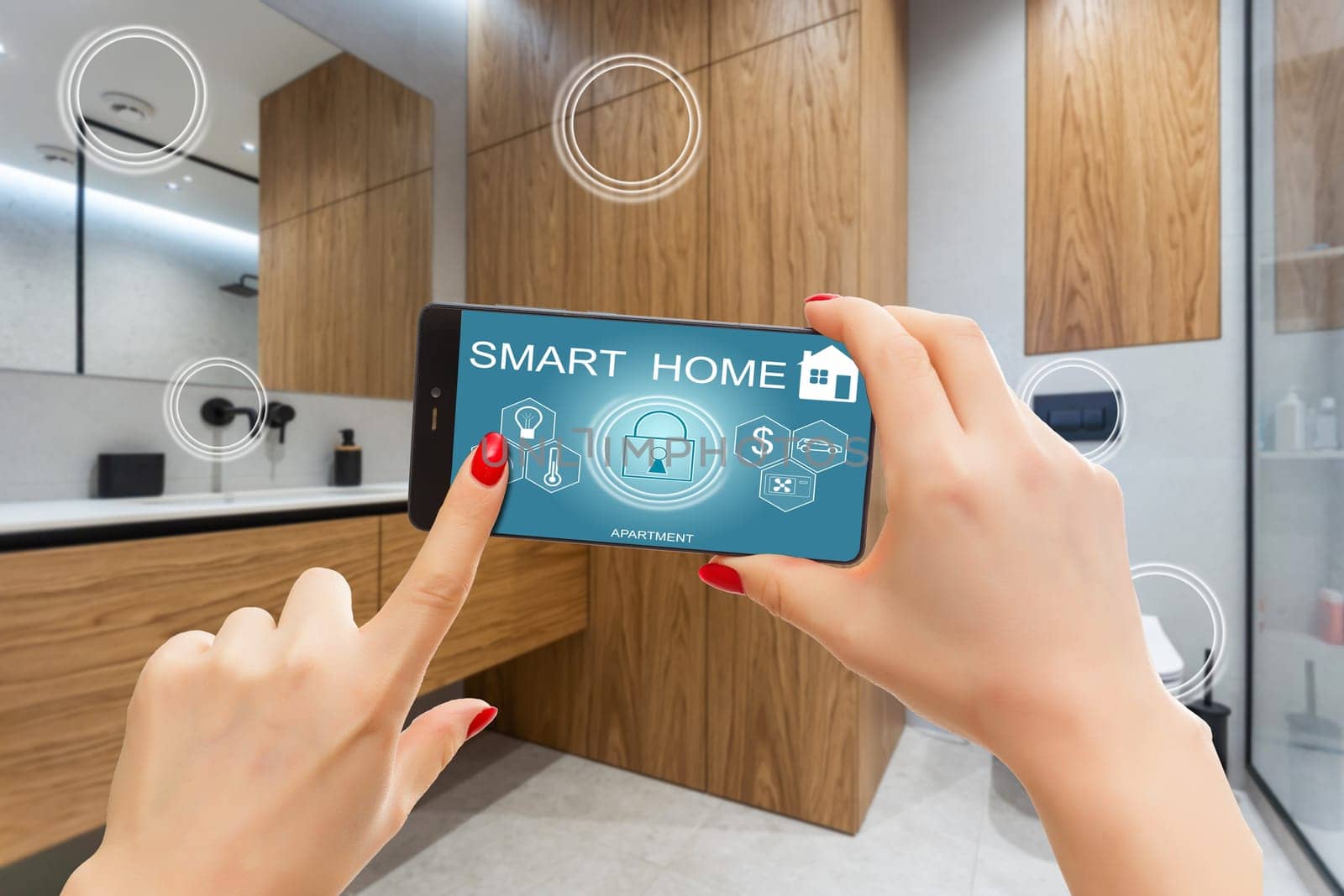 Smart home automation app on smartphone hold by female hand with home interior in background by Andelov13