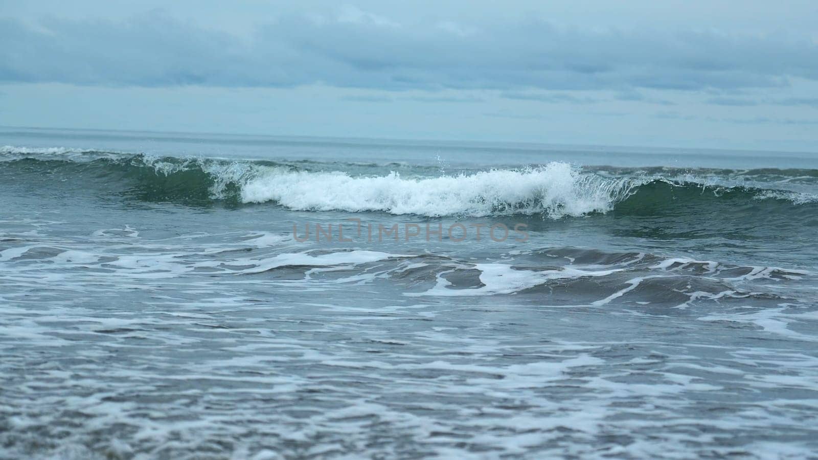 Seascape of beautiful waves on cloudy day. Clip. Beautiful coastal waves on background of horizon with cloudy sky. Coastal waves of North Sea on cloudy day.