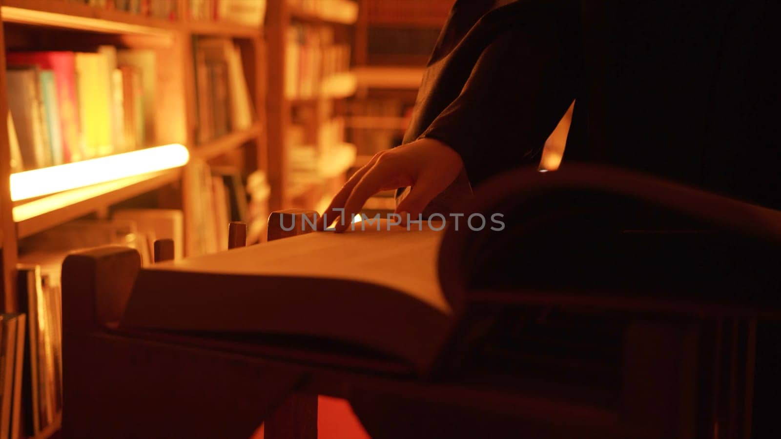 Close-up of mysterious man opening large book. Stock footage. Man opens book in dark library with flashing light. Secret society with mysterious books in night library by Mediawhalestock