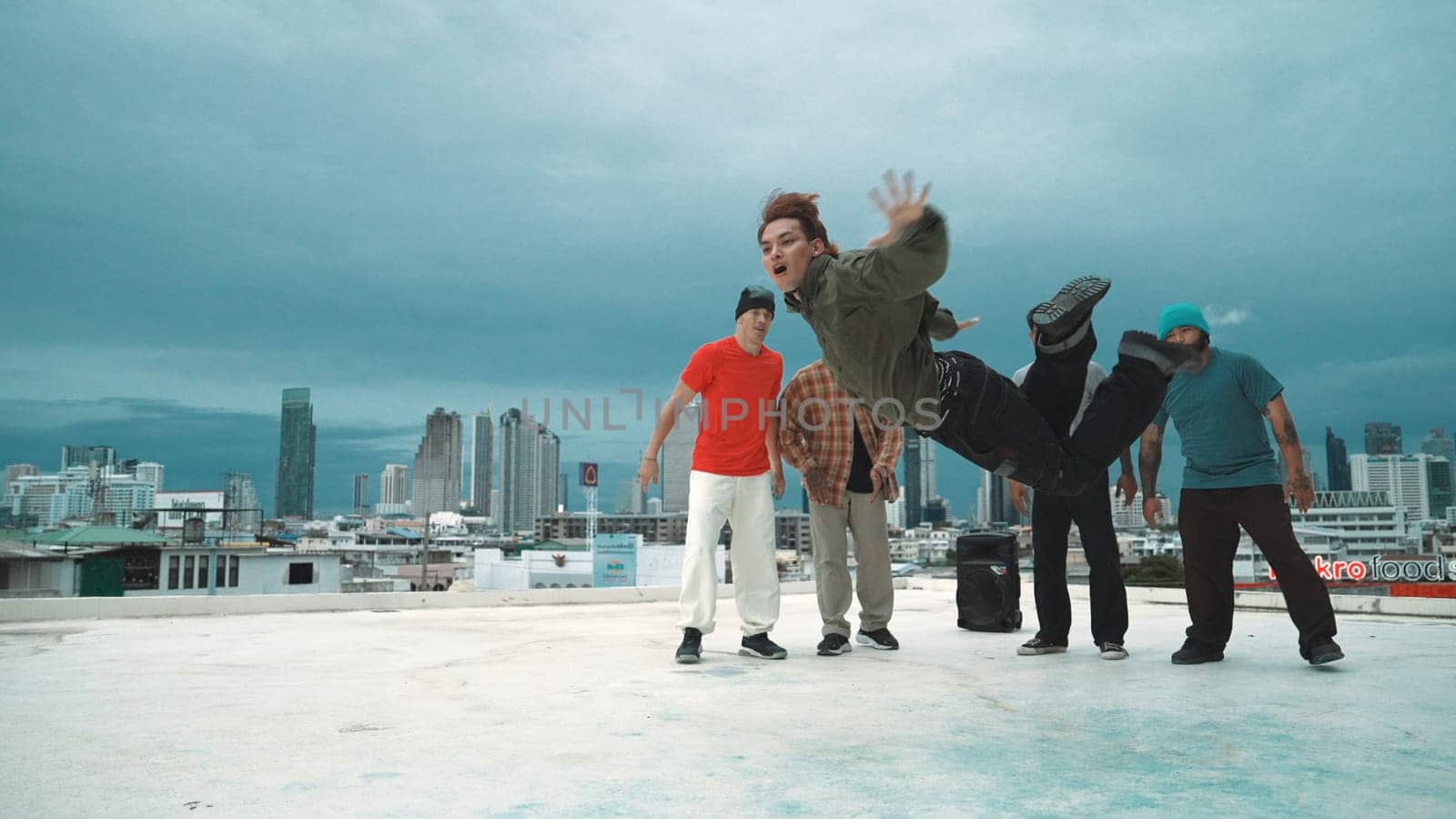 Hispanic hipster dancing surrounded by multicultural friend at city view with blue sky. Group of street dancer performing at rooftop. Active, fun, happy atmosphere. Outdoor sport 2024. Endeavor.