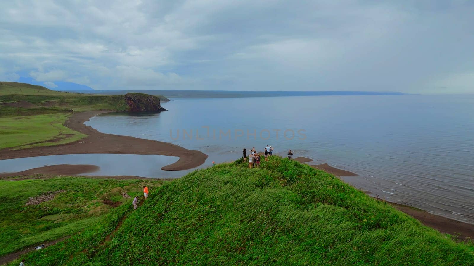 Aerial view of touristic group on a mountain top. Clip. People enjoying giant lake landscape