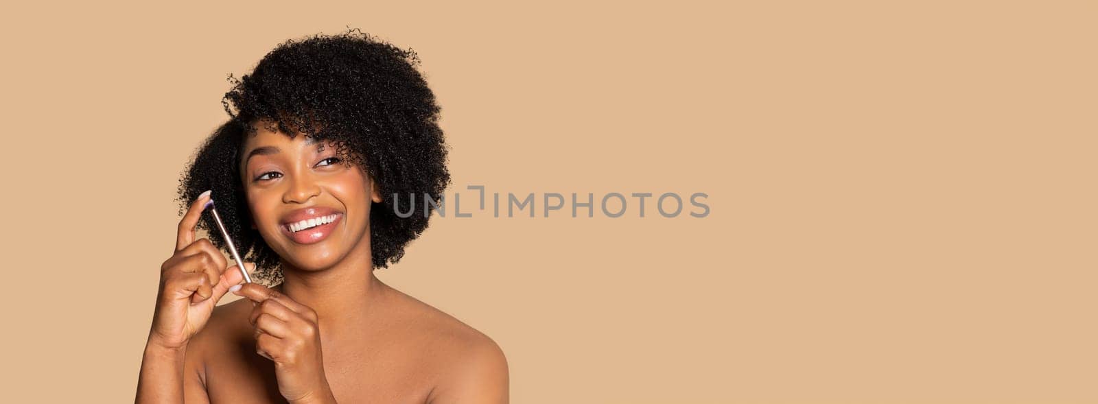 Gleeful black woman showcasing her flawless complexion and curly hair, evoking beauty and happiness on beige tone, free space, panorama