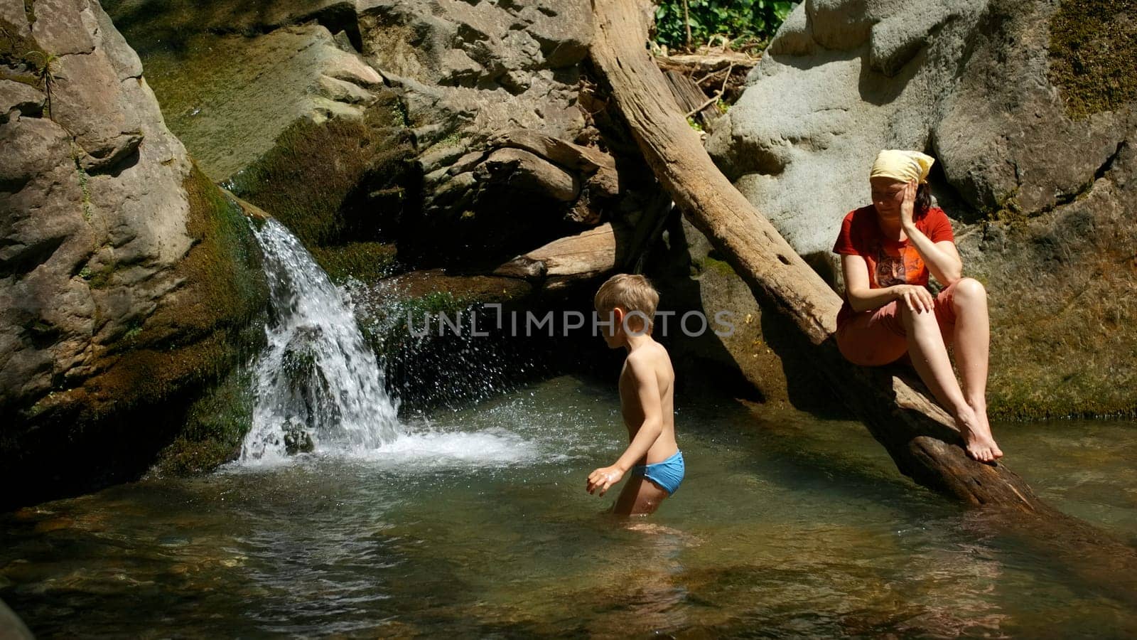 Mom with boy child in tropical waterfall. Creative. Family of hikers on a summer trip in jungles