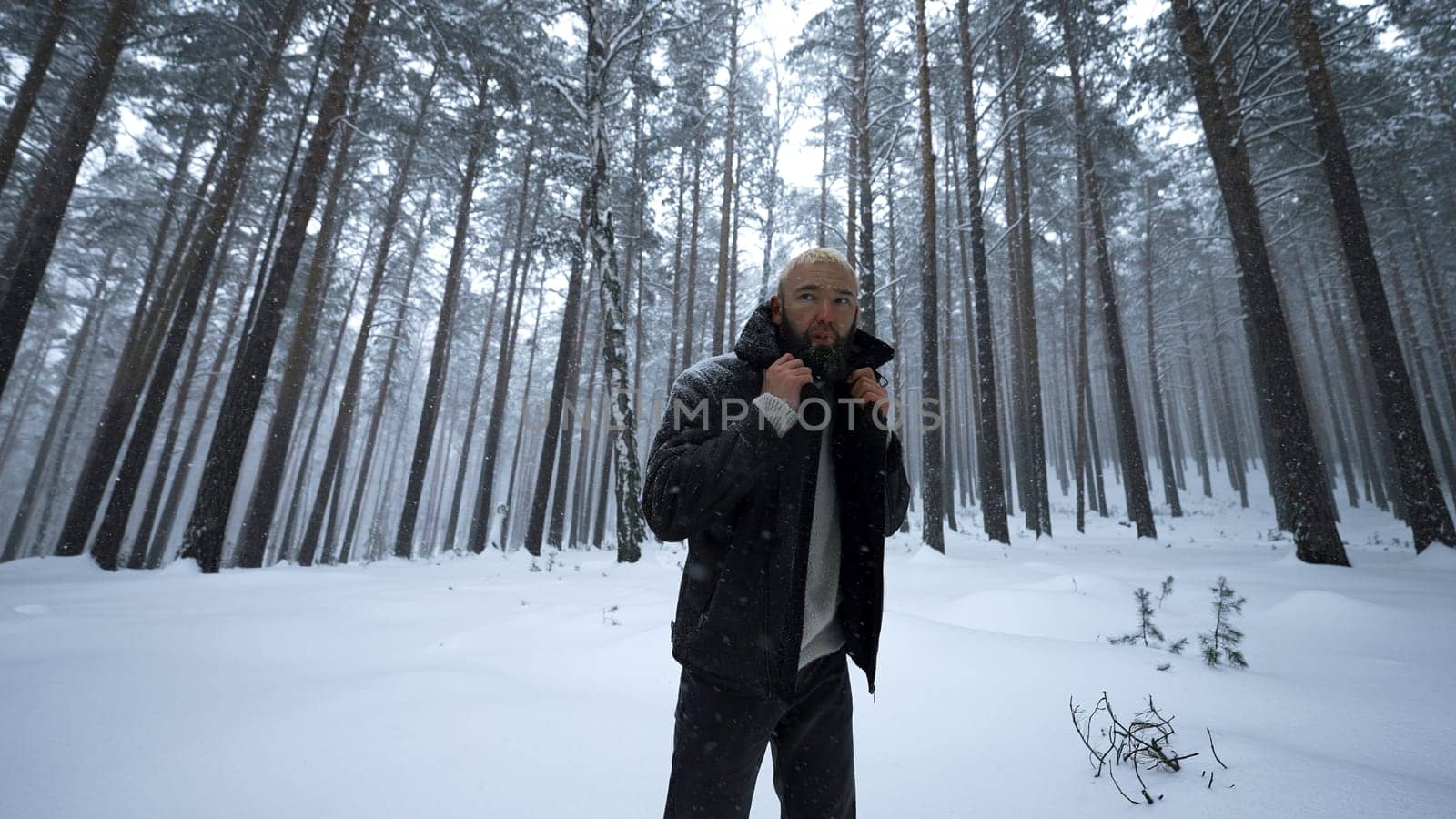 Stylish man poses in winter forest. Media. Shooting stylish man in winter forest. Fashion shooting of man in winter forest.