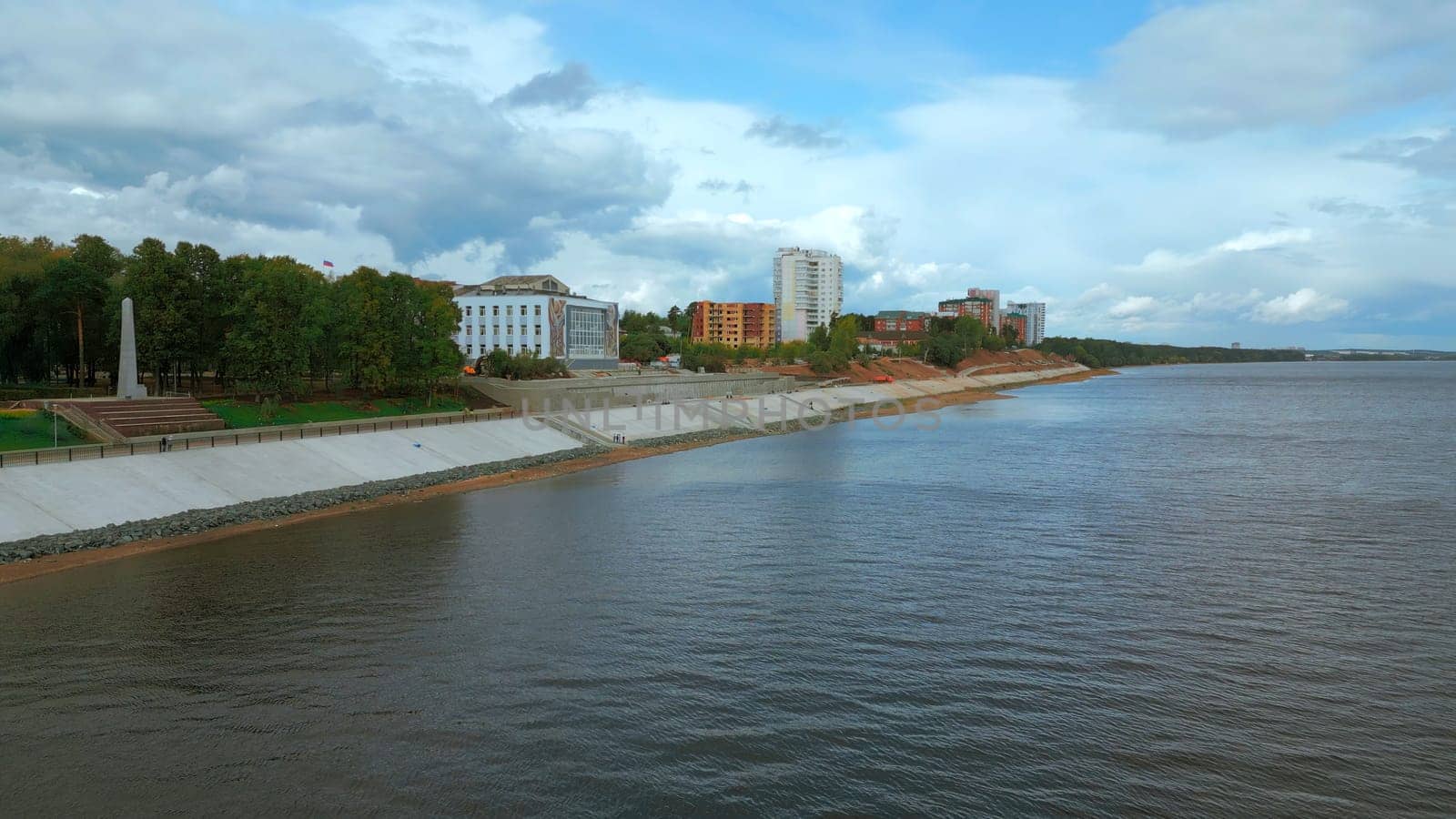 Top view of river embankment of city with forest. Clip. Landscaped embankment of city river bank. Beautiful landscape of river embankment with city park.