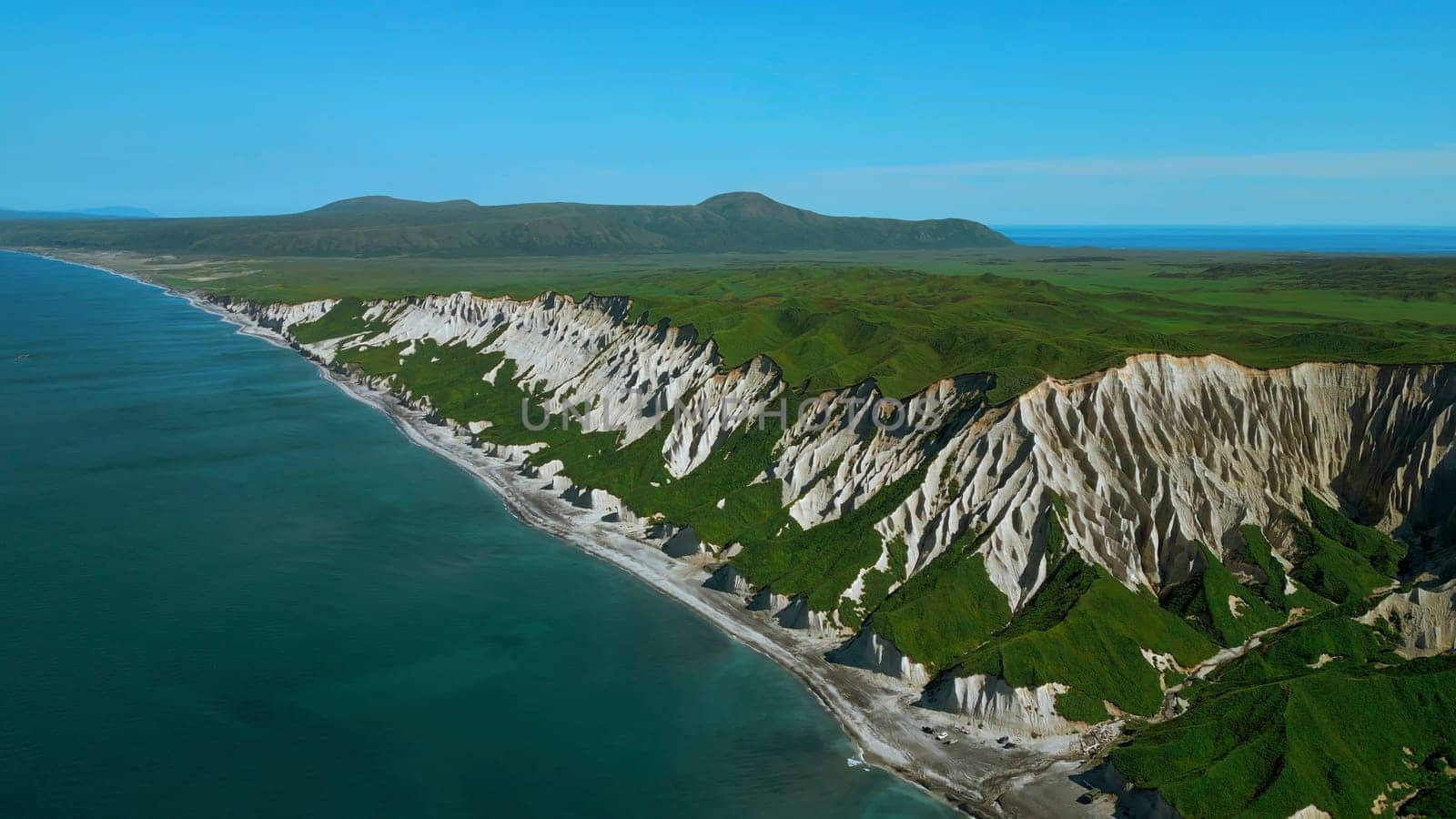 Bird eye view of calm ocean and stone rock cliffs at Oregon coast. Clip. Aerial of the ocean water surface and green meadows