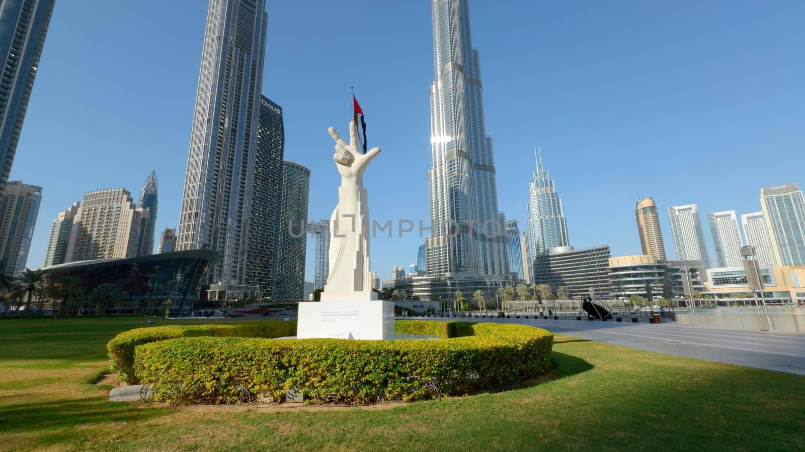 Camera moving towards sculpture with hand gesture: win, victory, love. Action. architecture and nature of sunny Dubai