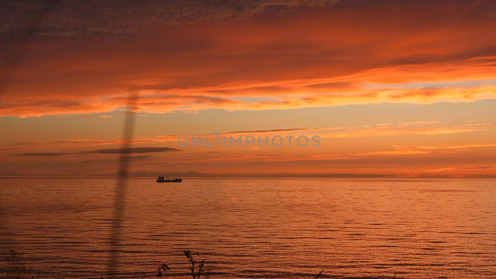 Beautiful seascape with sunset sky and ship on horizon. Clip. Magnificent view of sea sunset with red clouds and ship on horizon. Red sunset with beautiful sea and ship.