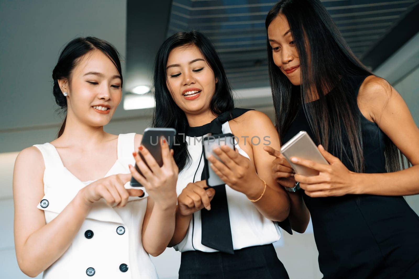 Three women friends having conversation while looking at mobile phone in their hands. Concept of social media, gossip news and online shopping. uds