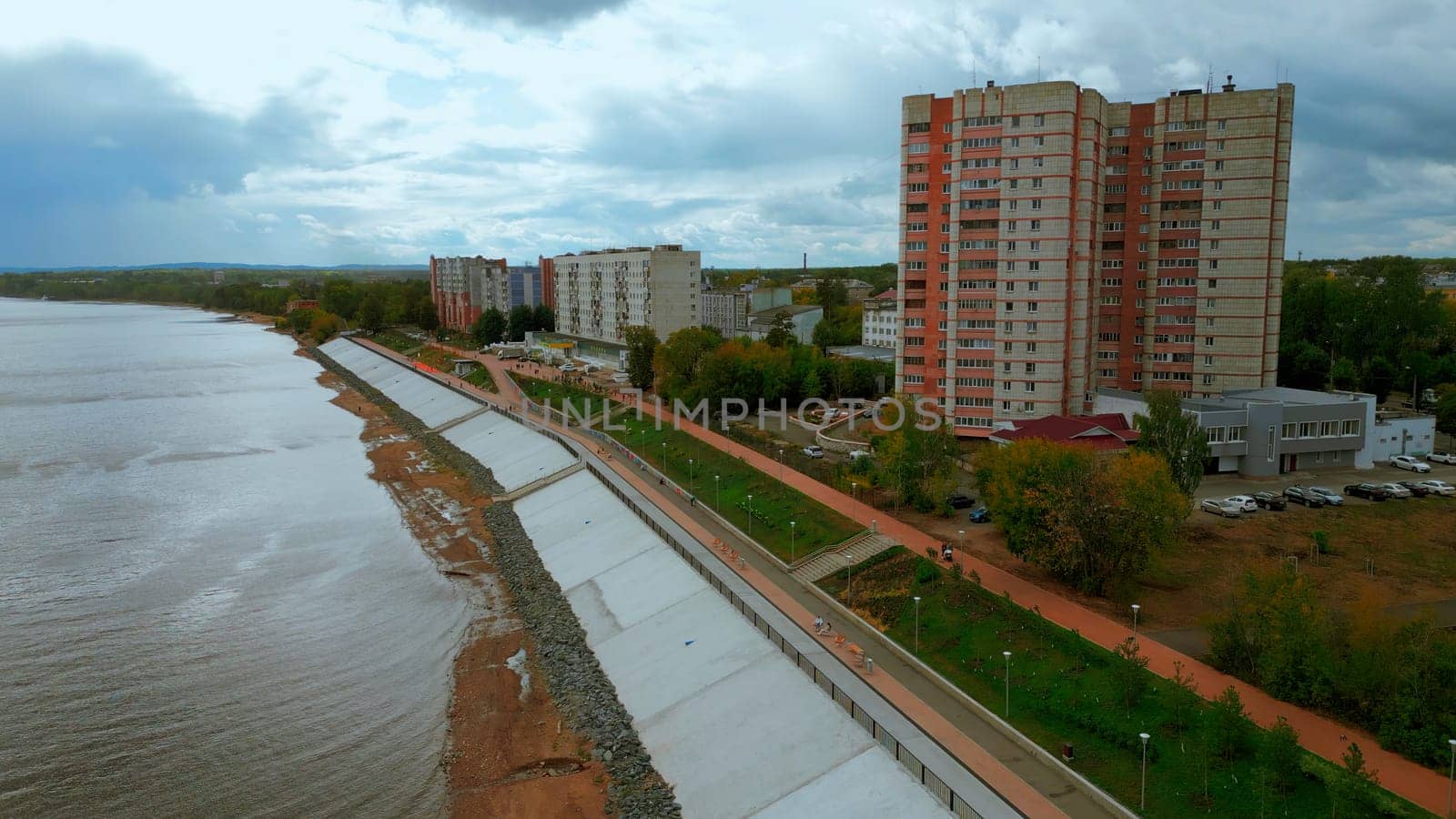 Aerial drone view of city river embankment. Clip. Urban cityscape with walking people