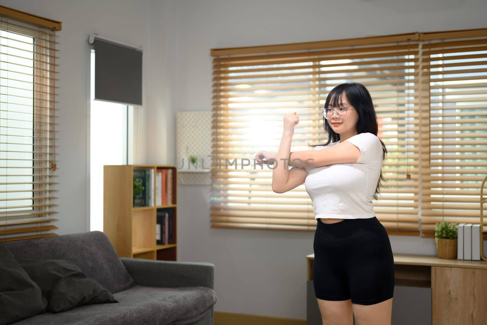 Pretty young woman doing stretching exercise in living room. Healthy lifestyle concept by prathanchorruangsak