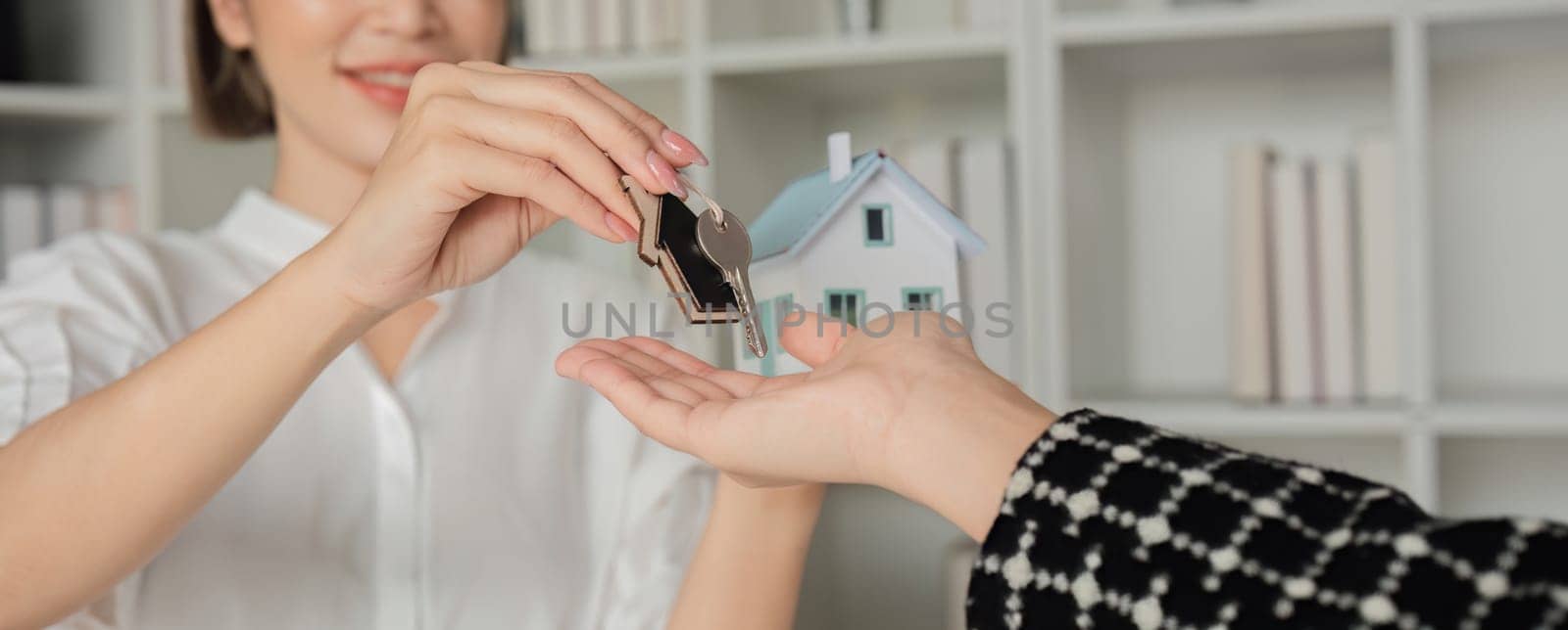 Real estate agent with house plans and keys given to the client after the purchase agreement is reached and the contract is signed. by wichayada