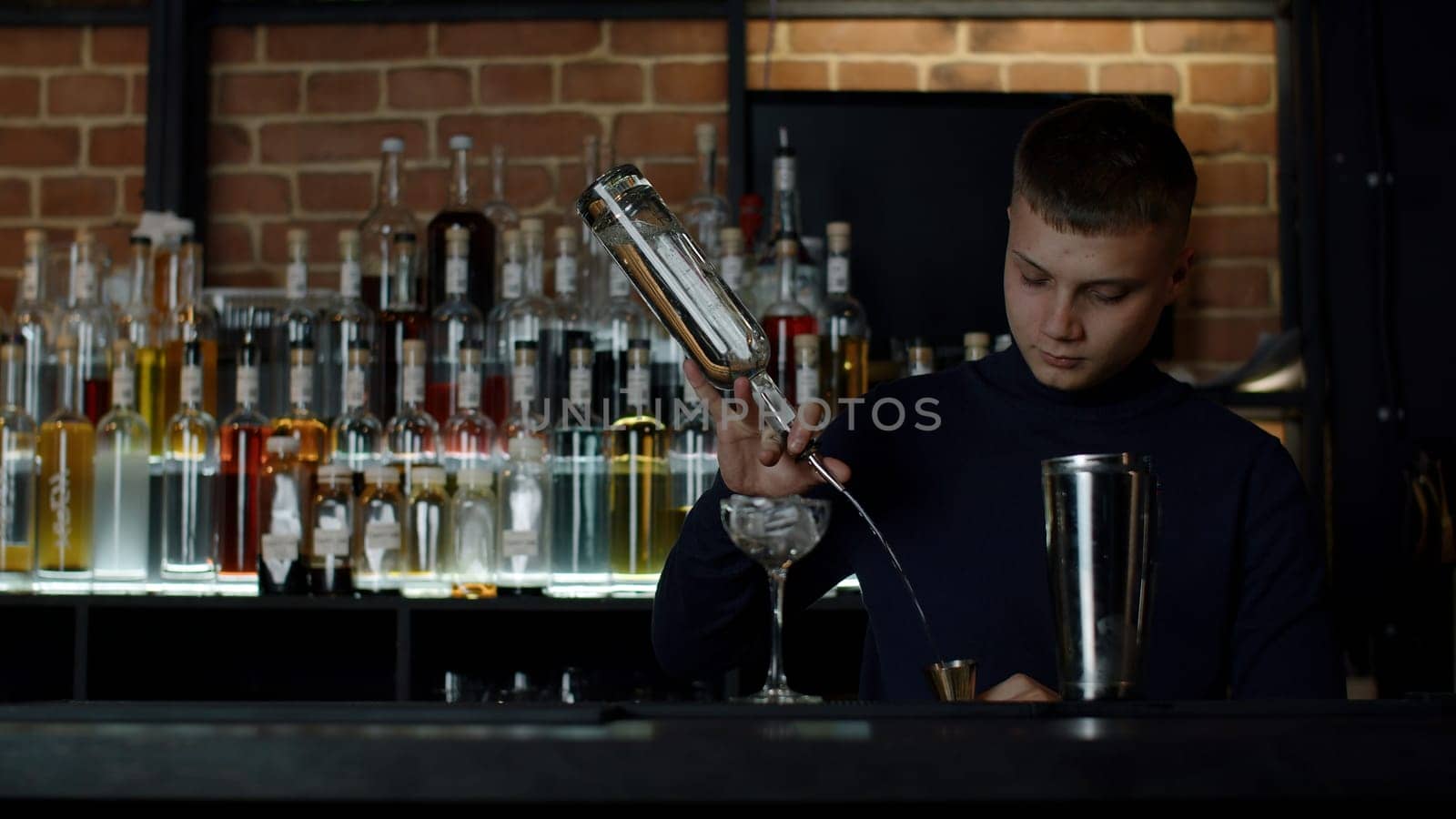Cool professional caucasian bartender making a cocktail. Media. Authentic barman making alcohol beverages in modern bar