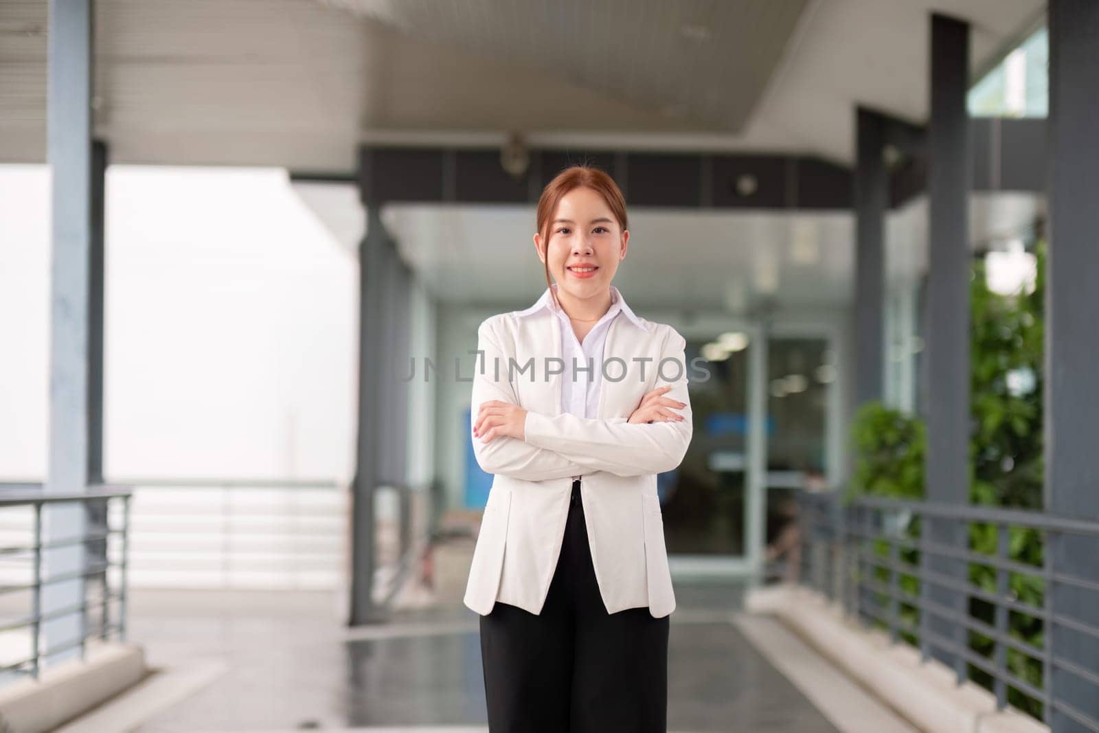 Young happy smiling professional business woman asian, happy confident positive female entrepreneur standing on street arms crossed, looking at camera by nateemee