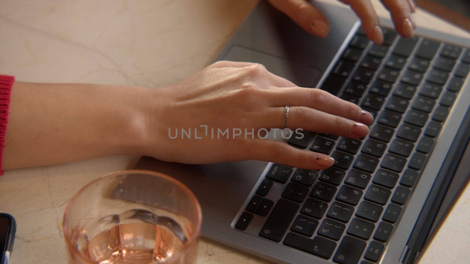 Close-up of beautiful woman typing on laptop. Stock footage. Beautiful female hands are typing on laptop keyboard. Female freelancer works at laptop in cafe.