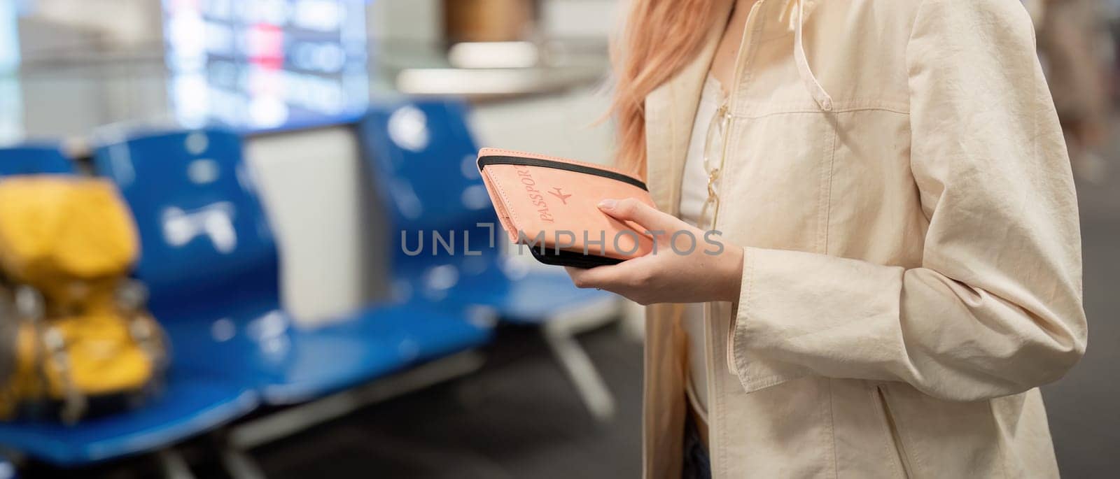 Hand of woman passenger holding passport with the flight in airport terminal.
