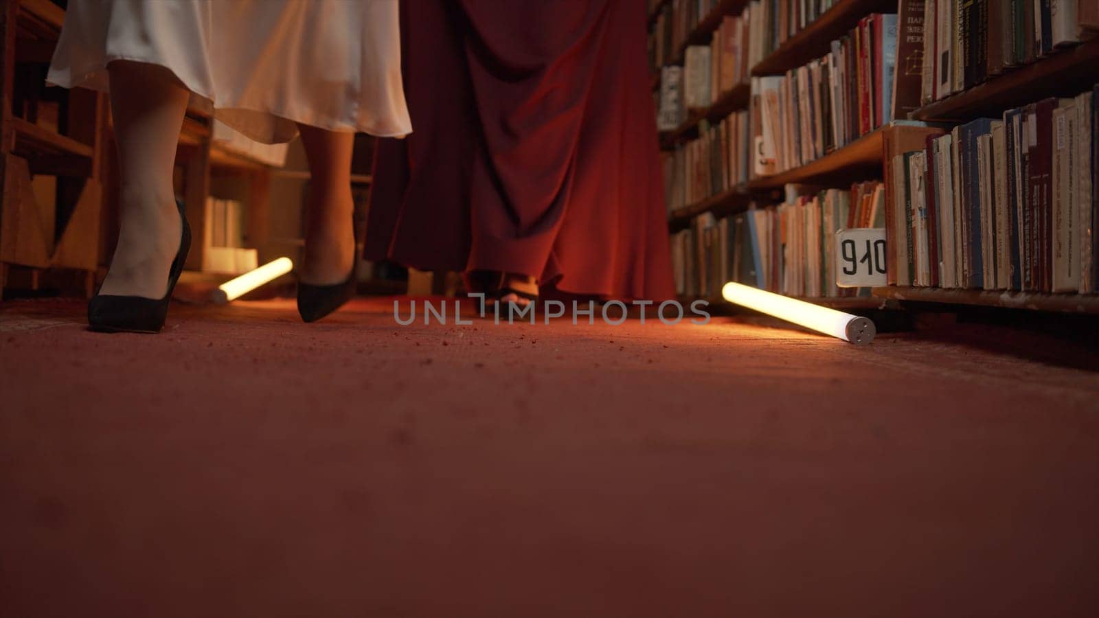 Women are mysteriously walking in library. Stock footage. Secret sorority in night library. Elegant women mysteriously gather in night library with flashing light.