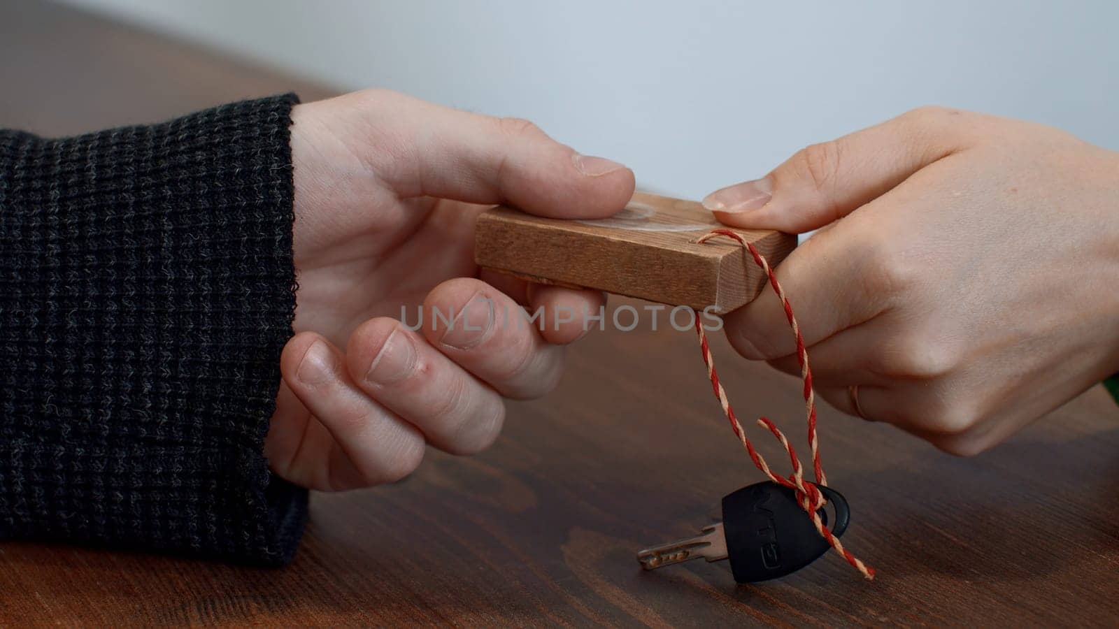 Close up of woman hand giving a key to a male hand on wooden desk background. Media. Taking a key at the fitness club reception