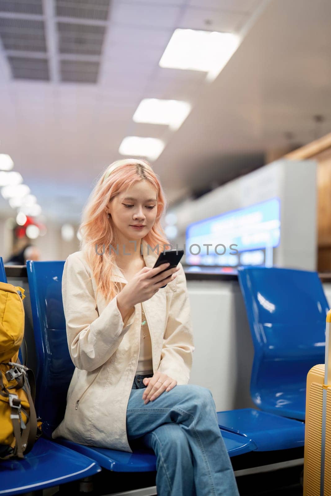 Happy asian tourist woman using mobile smartphone with suitcase traveling between waits for flight in Airport Terminal, flight check in, Tourist journey trip concept by nateemee