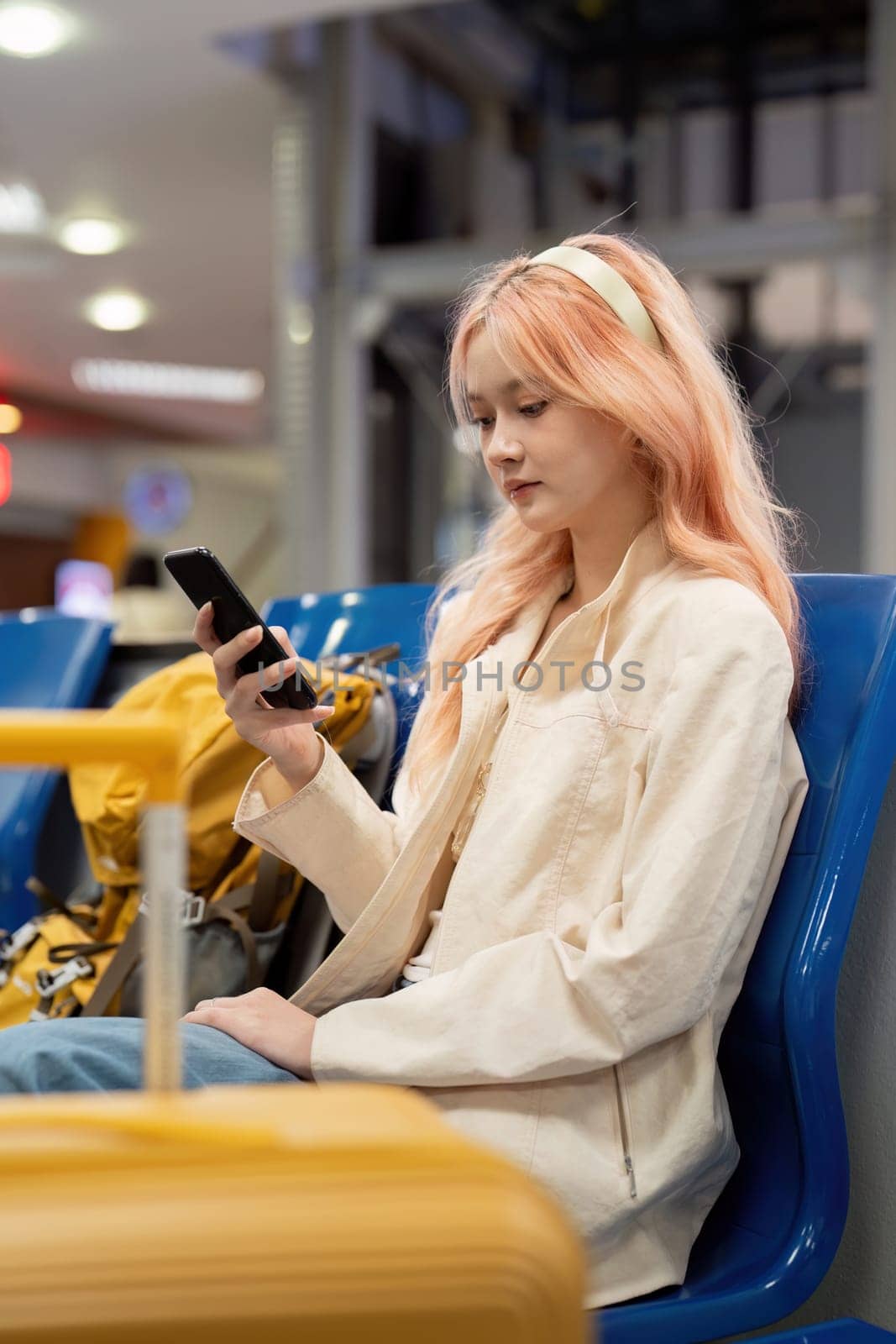 Happy asian tourist woman using mobile smartphone with suitcase traveling between waits for flight in Airport Terminal, flight check in, Tourist journey trip concept by nateemee