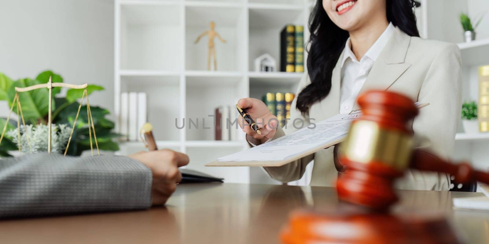 Two people are sitting at a table with pens and papers in front of them. They are discussing something important