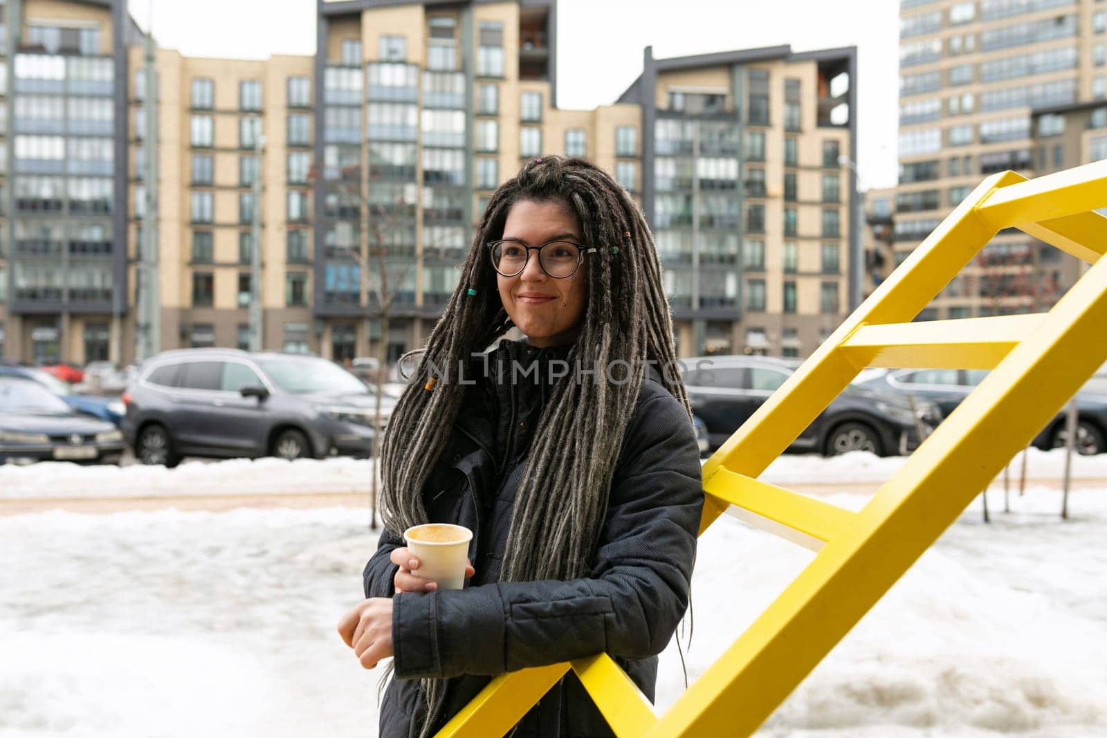 Photo on the street, young pretty informal woman wears dreadlocks hairstyle.