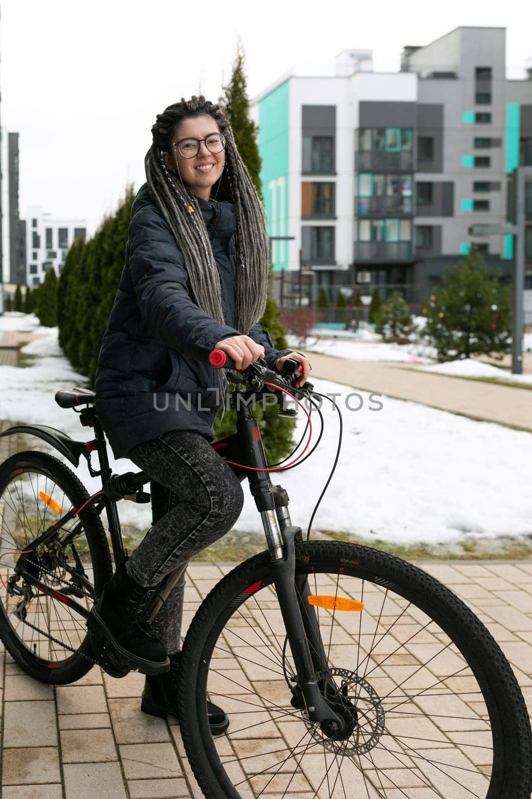 A pretty young woman with a dreadlocked hairstyle rides a rented bicycle by TRMK