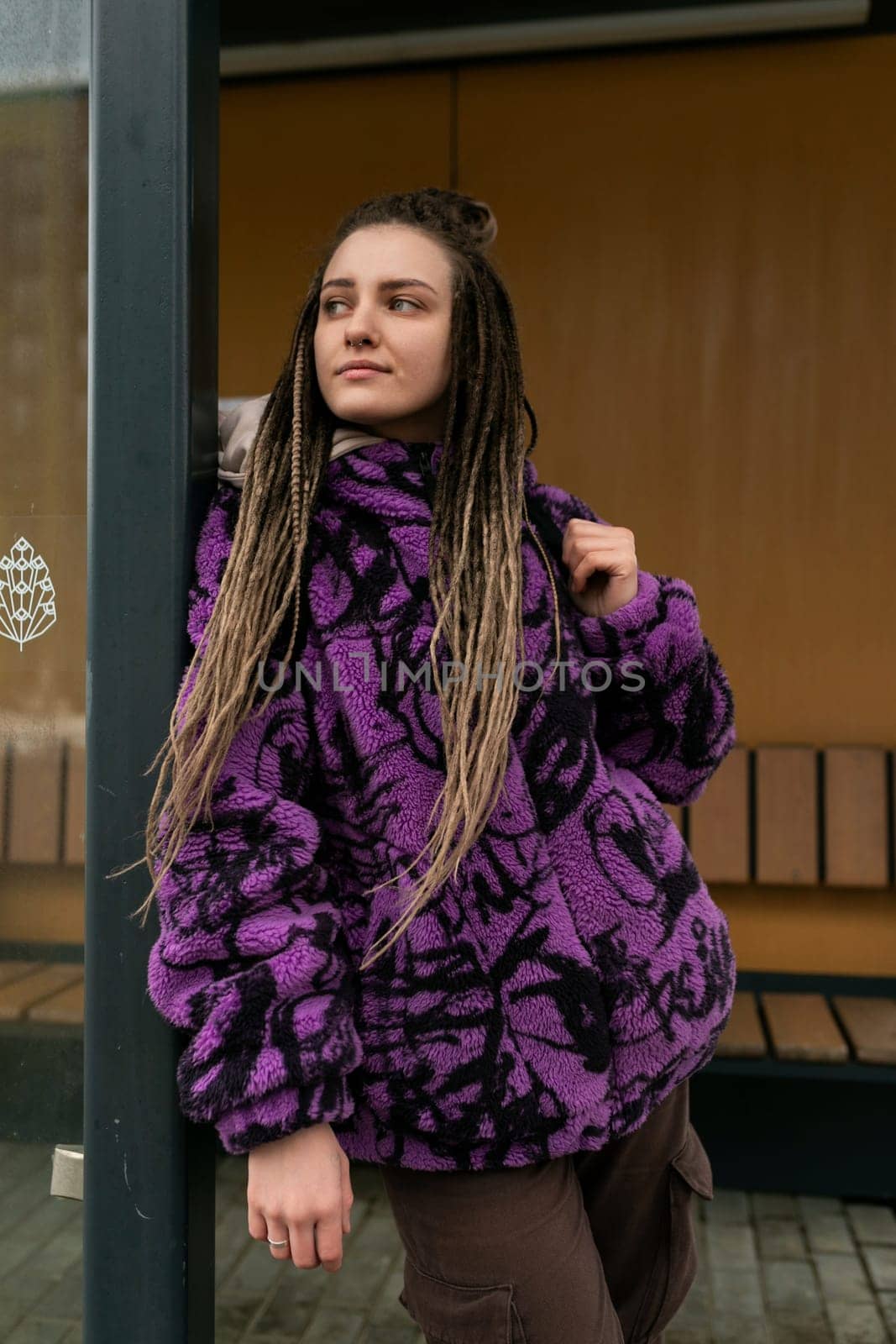 European woman with dreadlocks and piercings wearing a purple jacket by TRMK