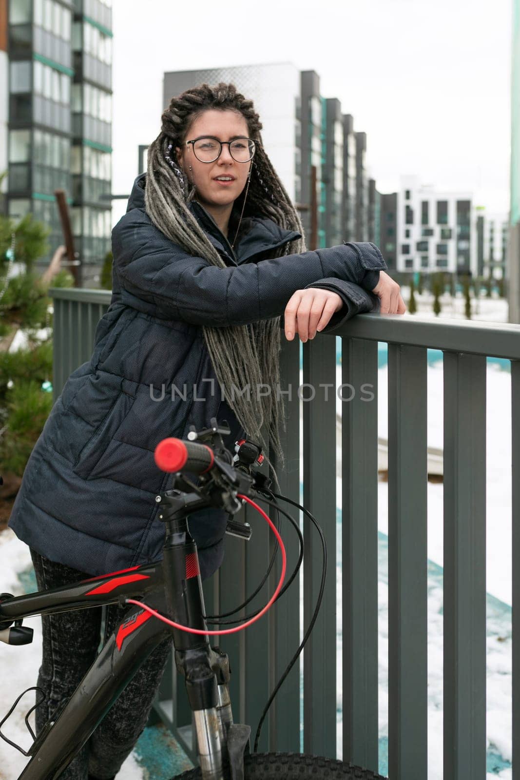 A pretty young woman with a dreadlocked hairstyle rides a rented bicycle by TRMK