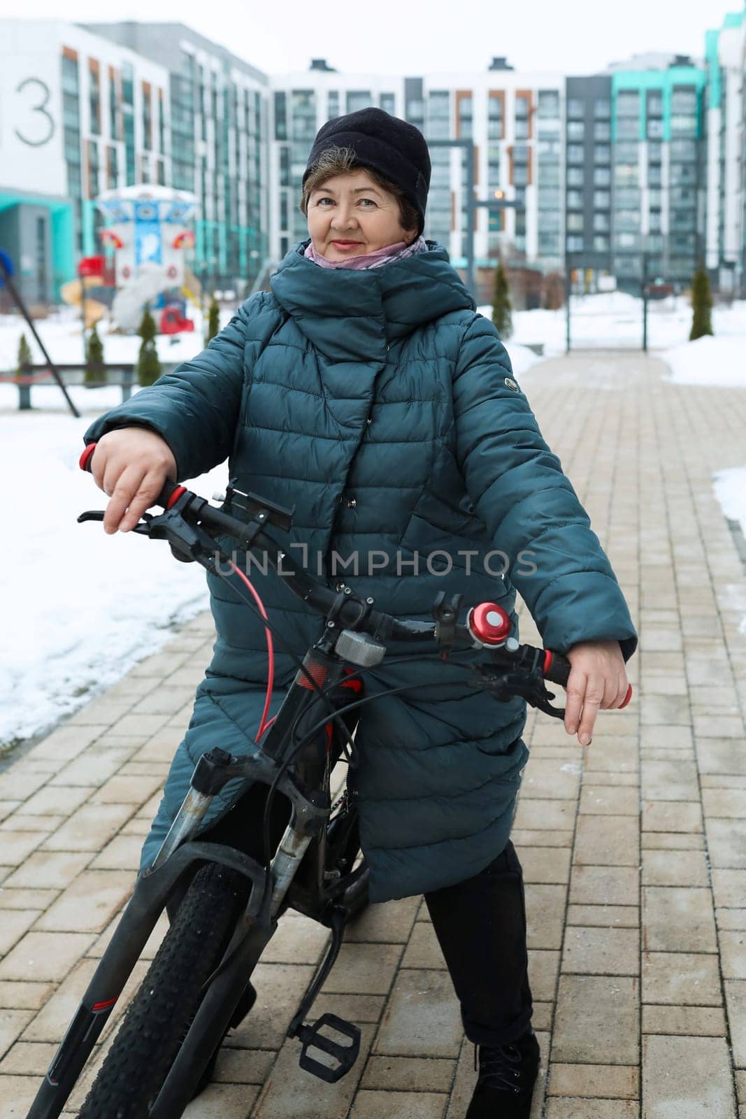 Healthy pensioner woman leads a healthy lifestyle and rides a bike in winter by TRMK