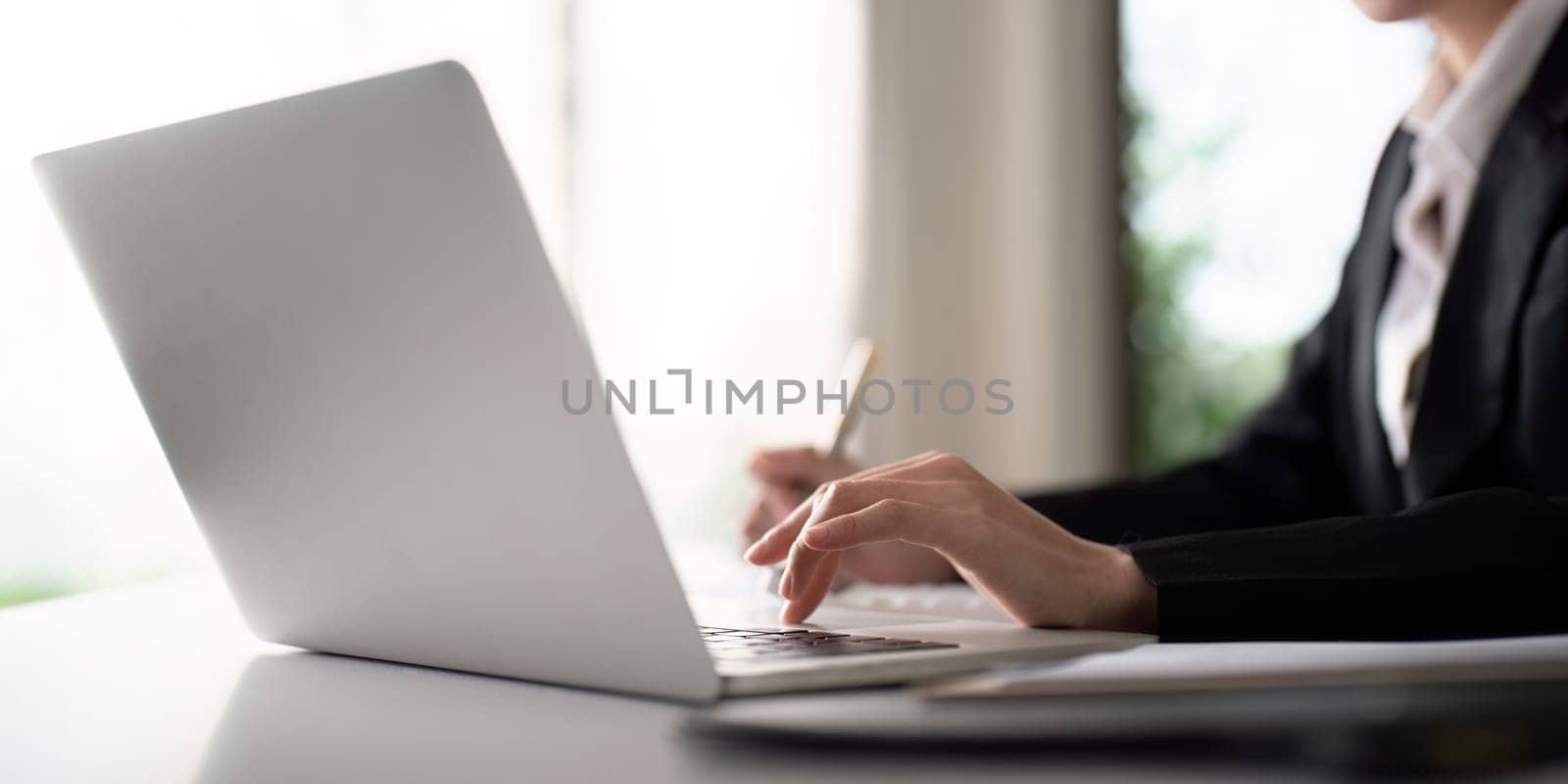 Business woman typing on laptop computer, searching and surfing the internet on office desk.